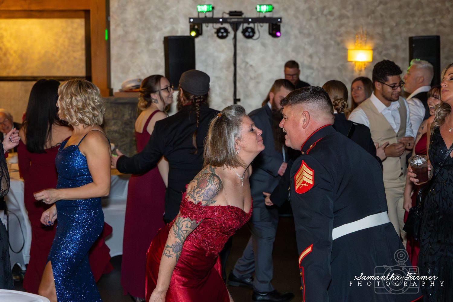 Wedding guests dancing and celebrating on a dance floor at an indoor reception venue with brick walls.
