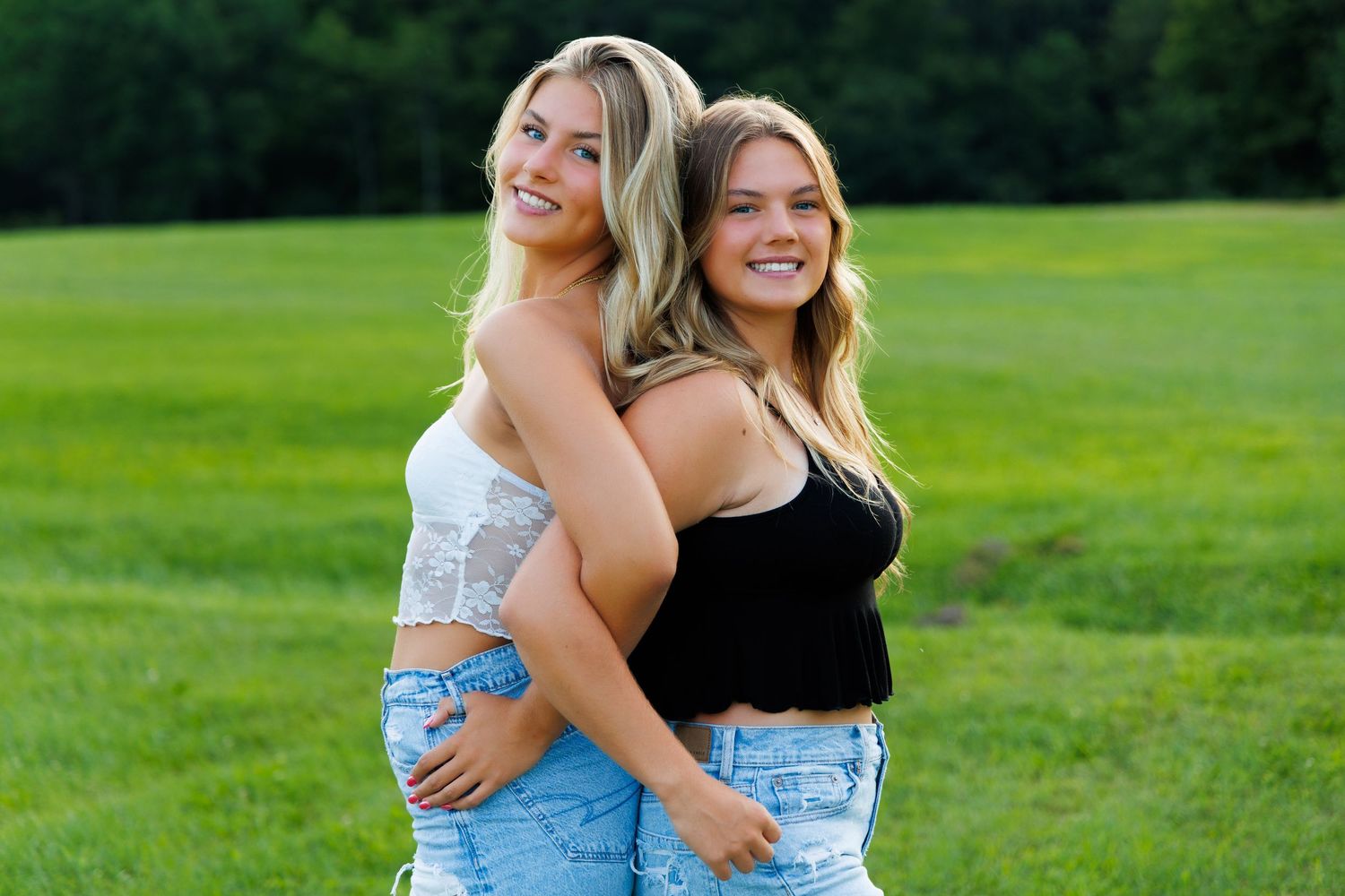 Friends enjoying a sunny day outdoors on green grass in casual summer outfits.