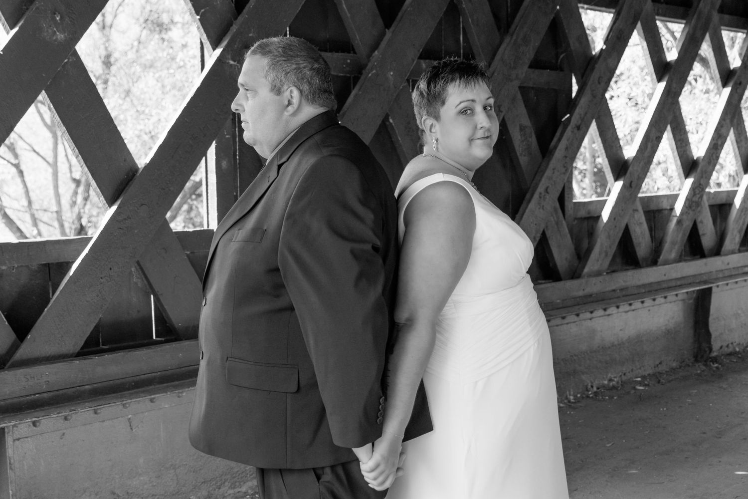 Wedding couple posing in a covered bridge for romantic portraits.