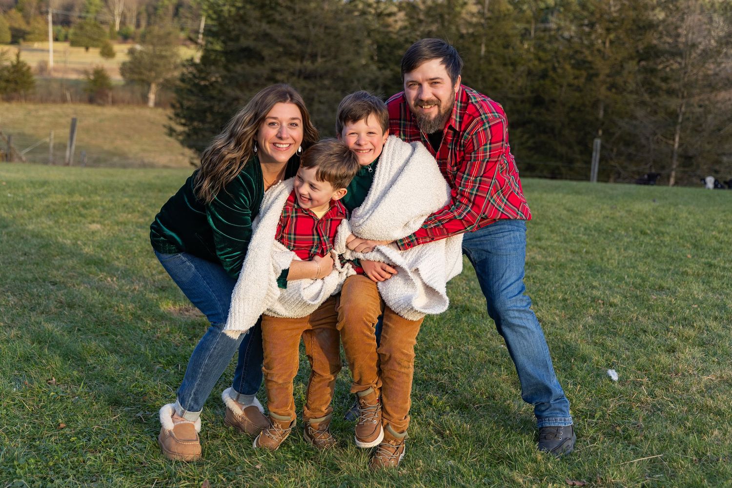 A family plays together on grassy hillside during golden hour outdoor photoshoot.