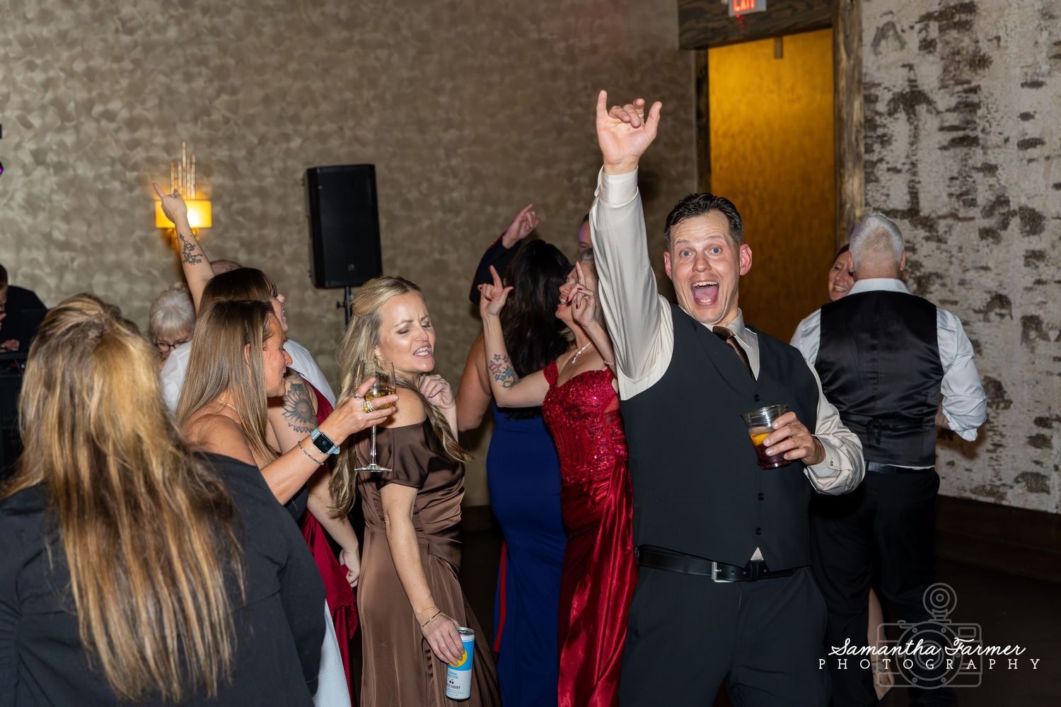 Celebration at a rustic venue with guests dancing and socializing under ambient lighting.