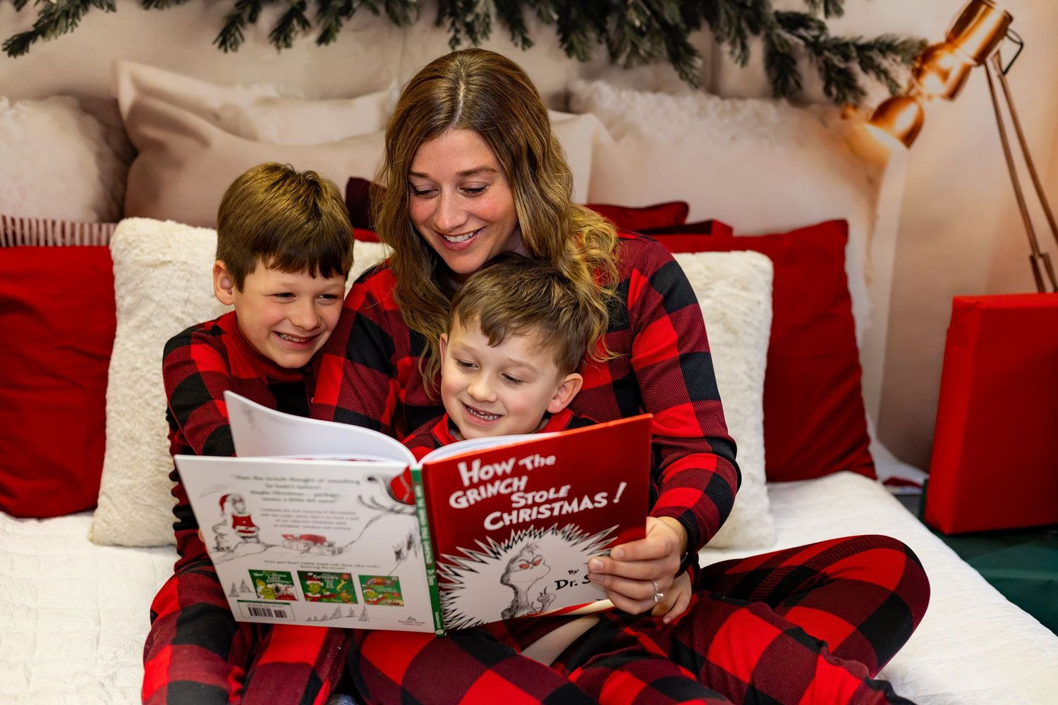 Cozy family reading Christmas stories in buffalo plaid pajamas.