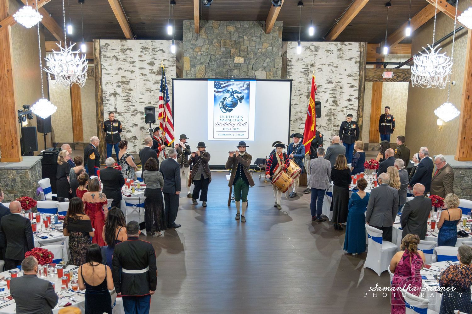 Large banquet hall with stone walls and wooden beams hosting a formal event.