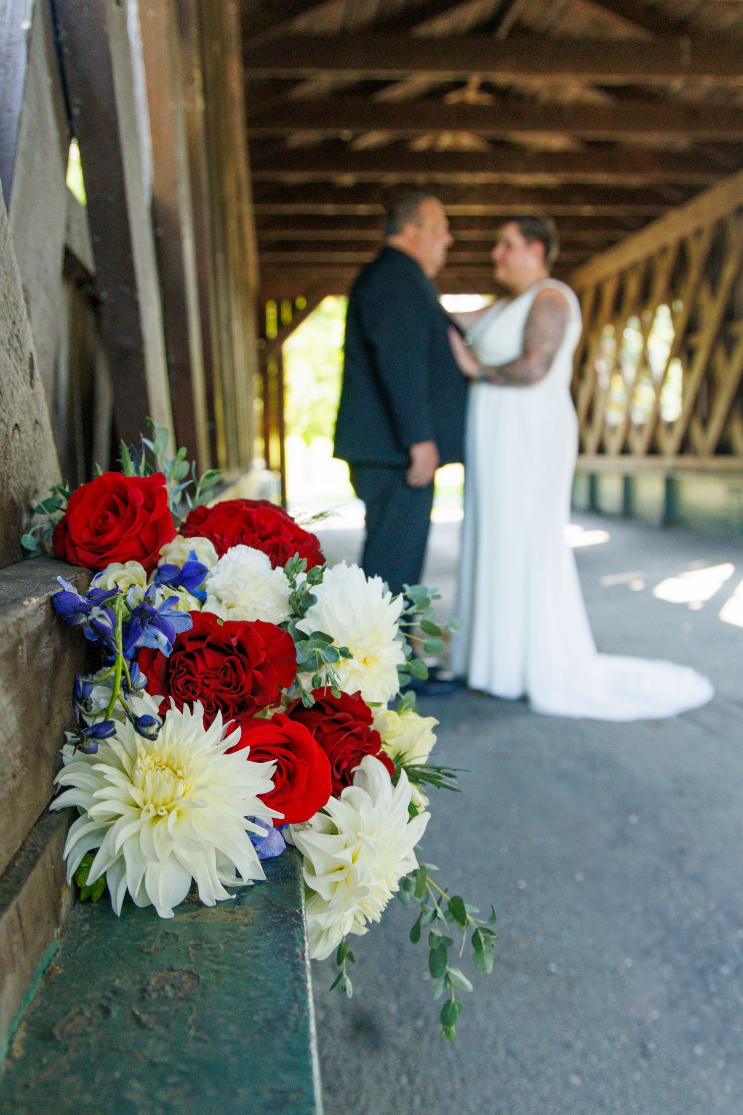 Red and white floral bouquet arrangements displayed in a covered bridge setting.