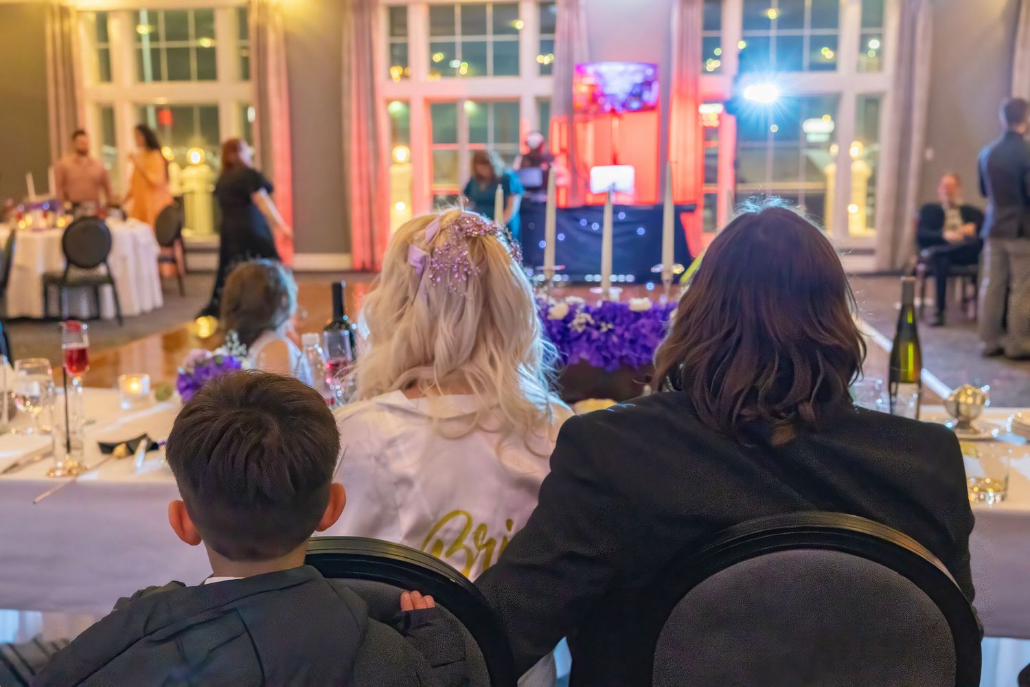 Wedding reception venue with colorful lighting and guests seated at decorated tables.