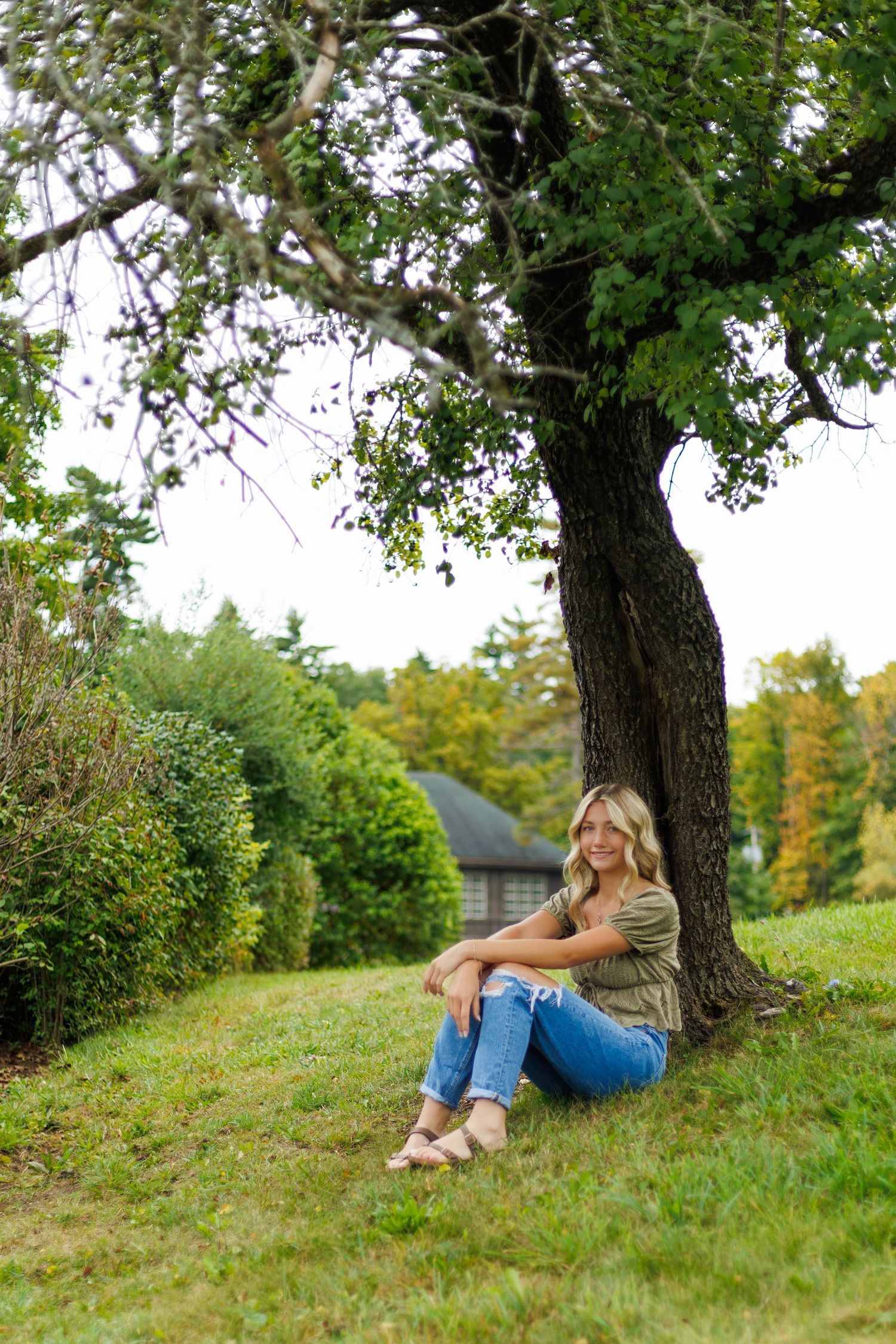 Natural outdoor portraits taken under a large tree on a grassy hillside.