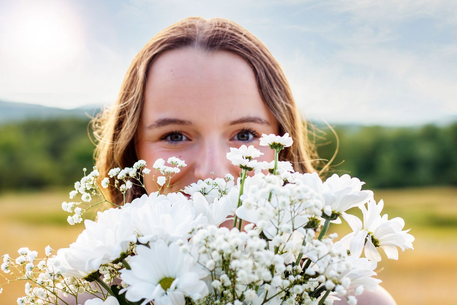 A bouquet of white flowers held up against a bright blue sky.