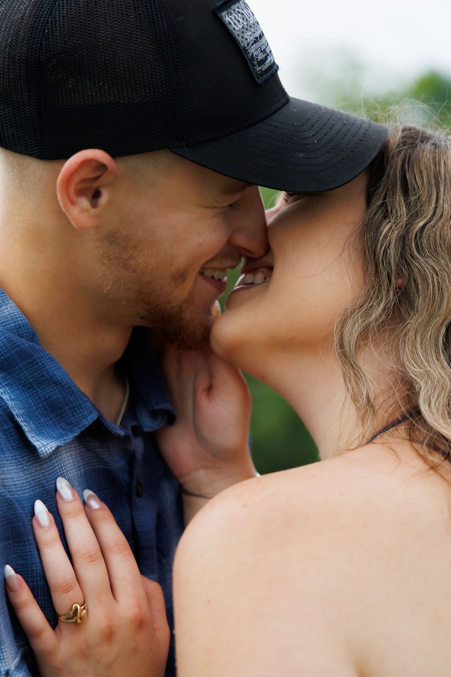 A close-up intimate moment between a couple showing an engagement ring.