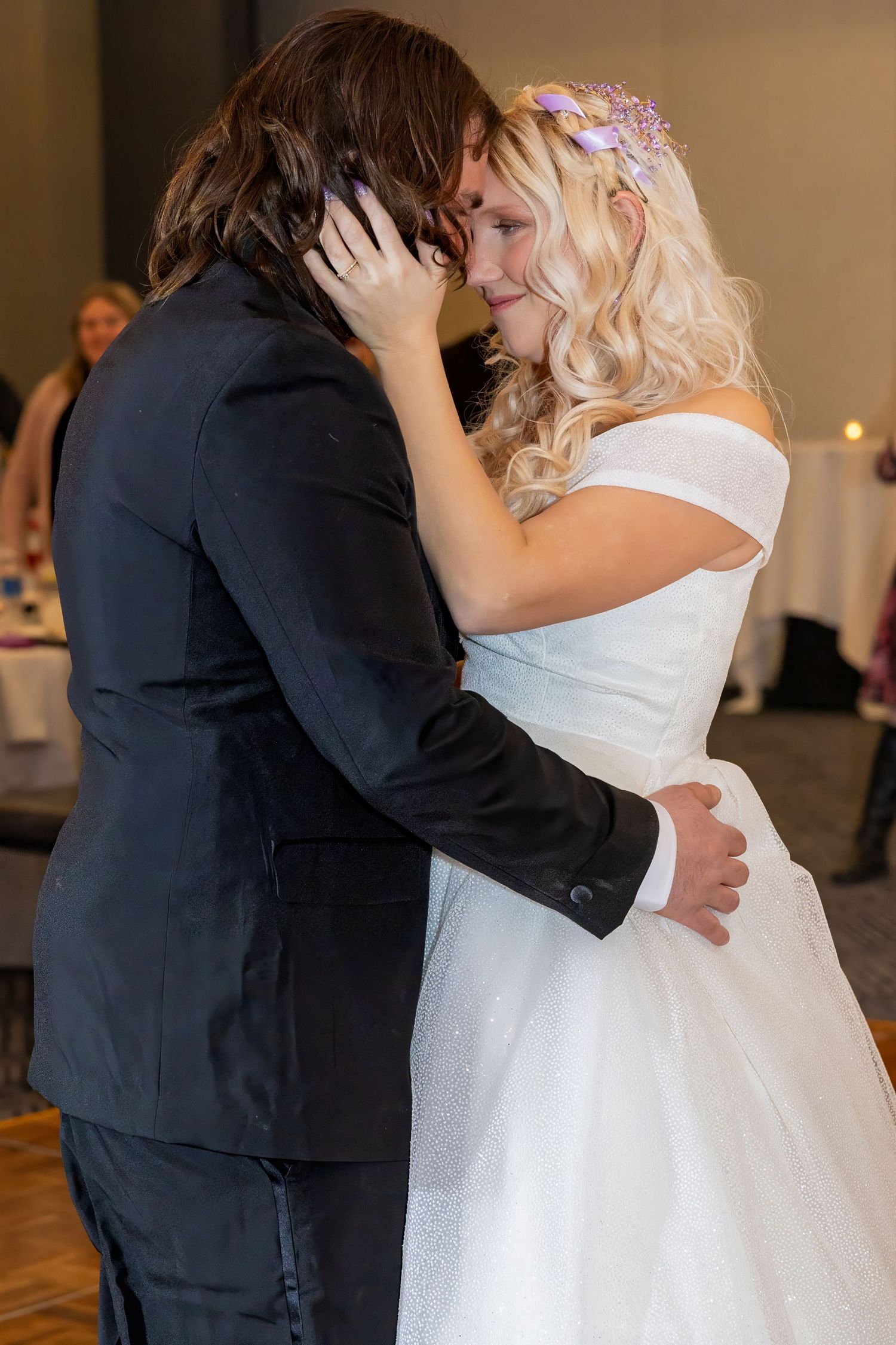 A romantic dance embrace between newlyweds in formal wedding attire.