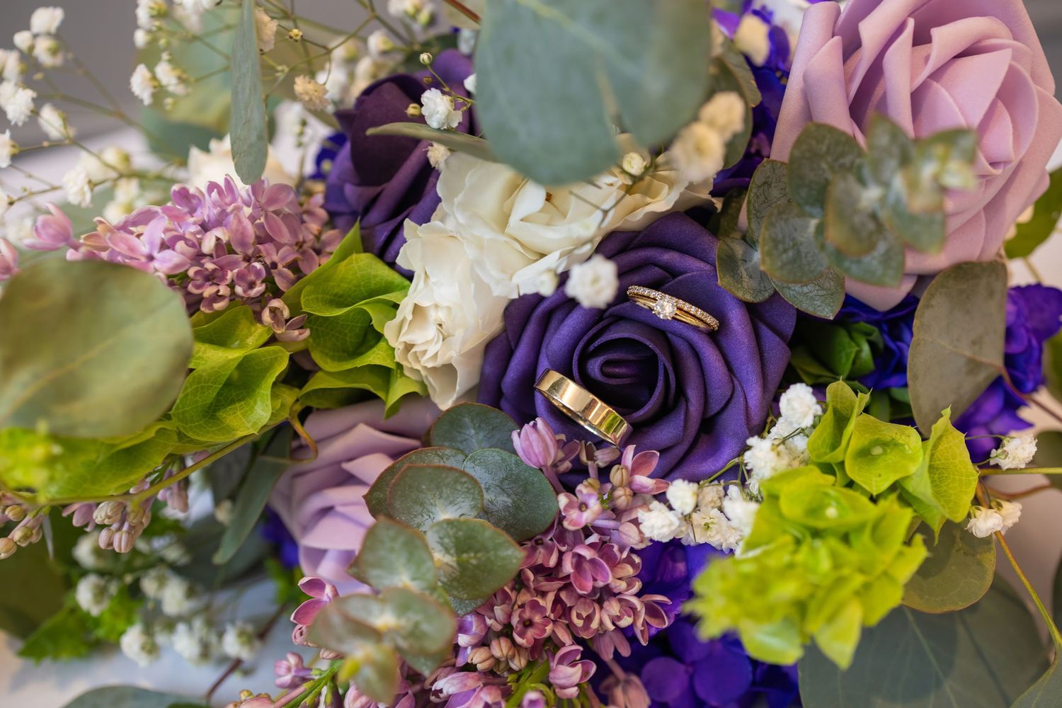 Wedding bouquet arrangement featuring purple, pink and green florals with eucalyptus leaves.