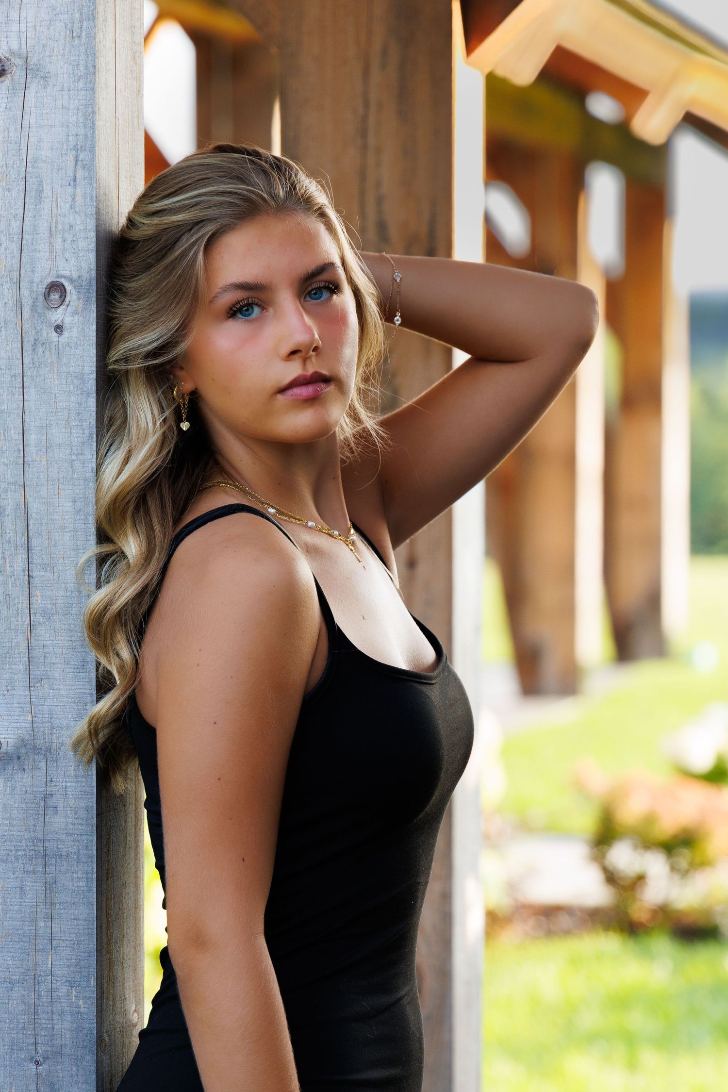 Portrait series in black tank top against wooden backdrop with natural lighting.