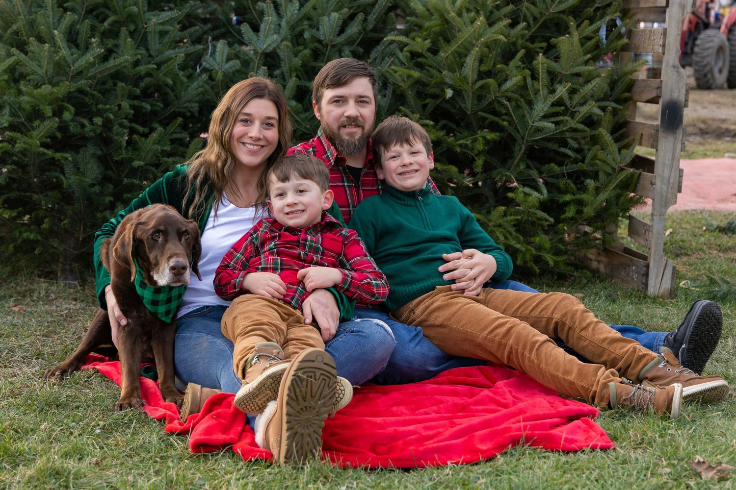 Family relaxing on red blanket during outdoor Christmas photo session.