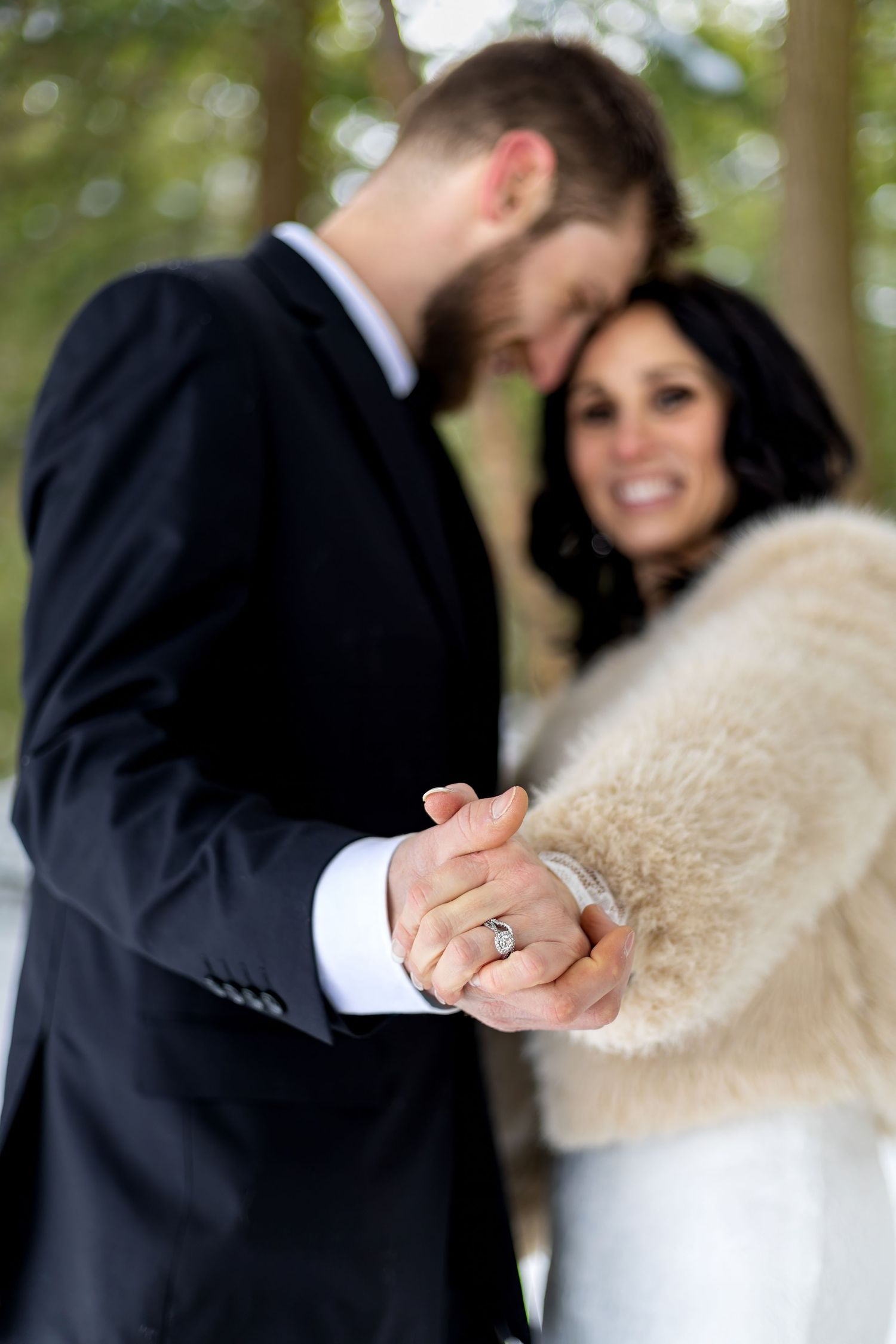 Romantic winter wedding couple holding hands in a snowy forest setting.