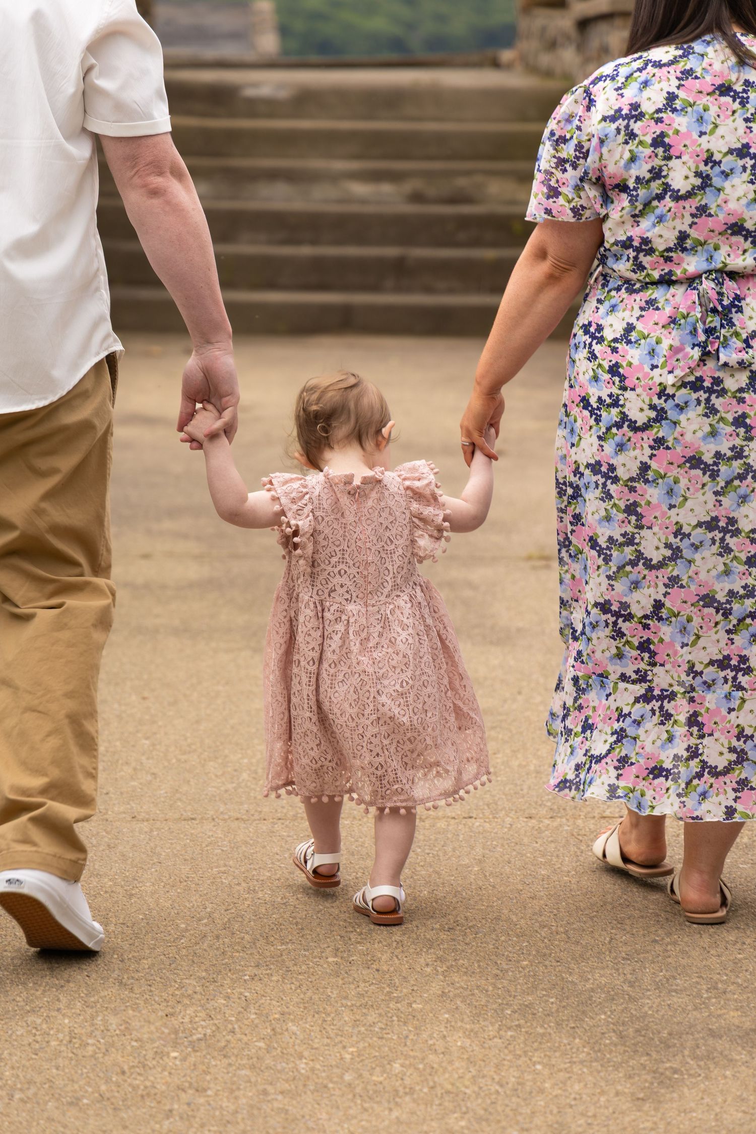 Close-up of tiny feet walking on concrete steps in floral and pink outfits.