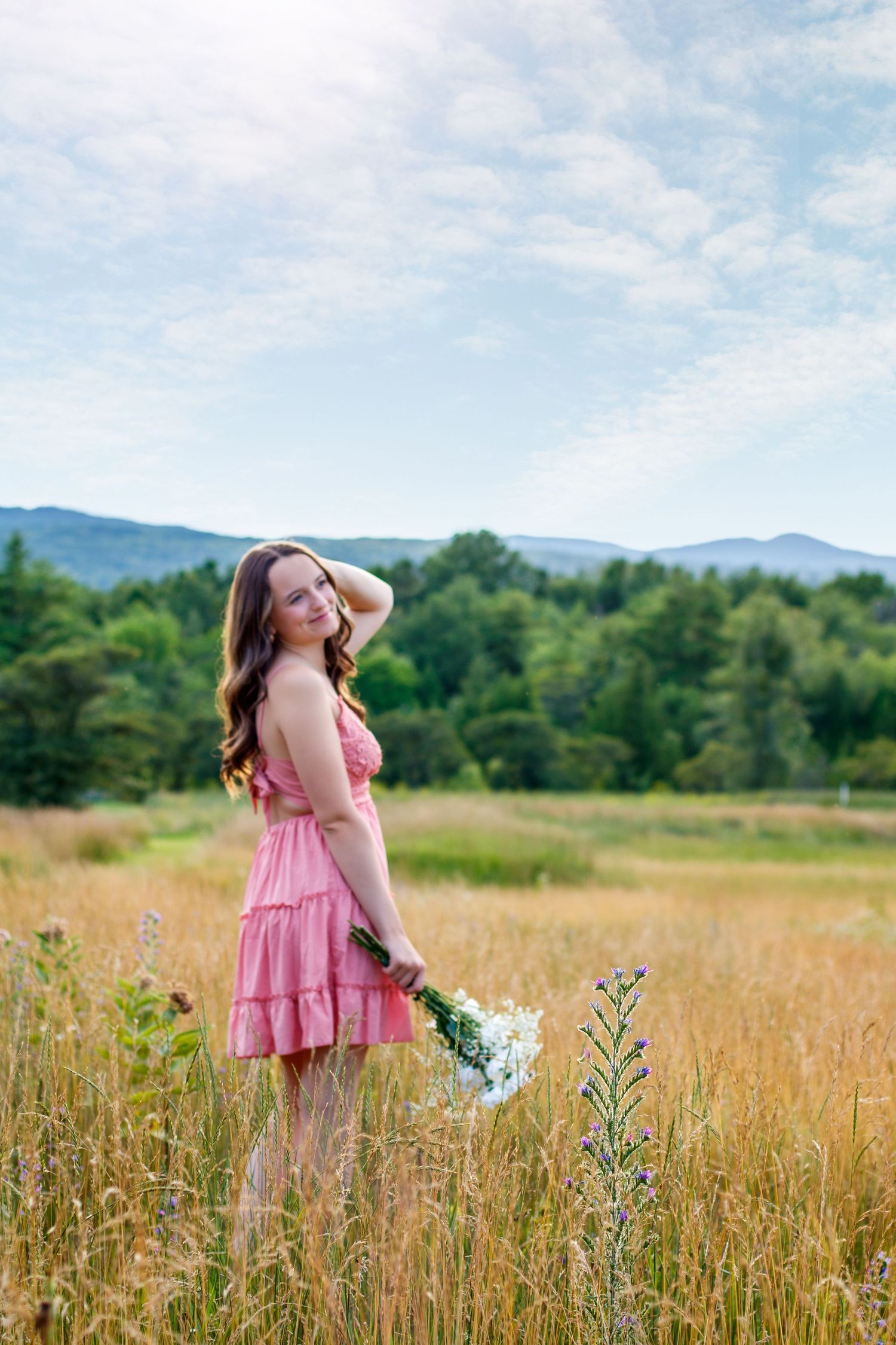 Someone in a pink dress twirling through a wildflower meadow on a sunny day.