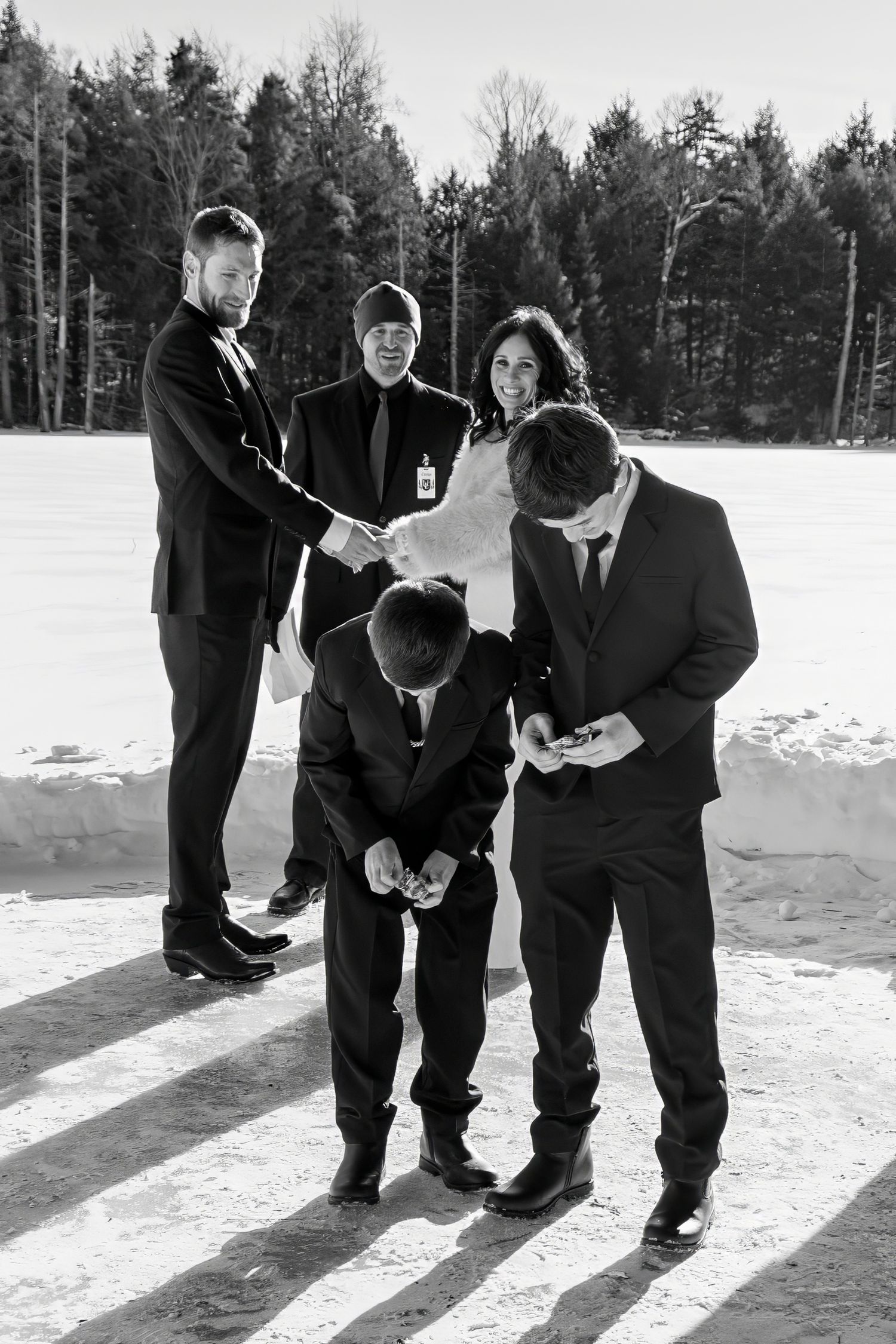 Wedding party members share candid moments in the snow during a winter ceremony.