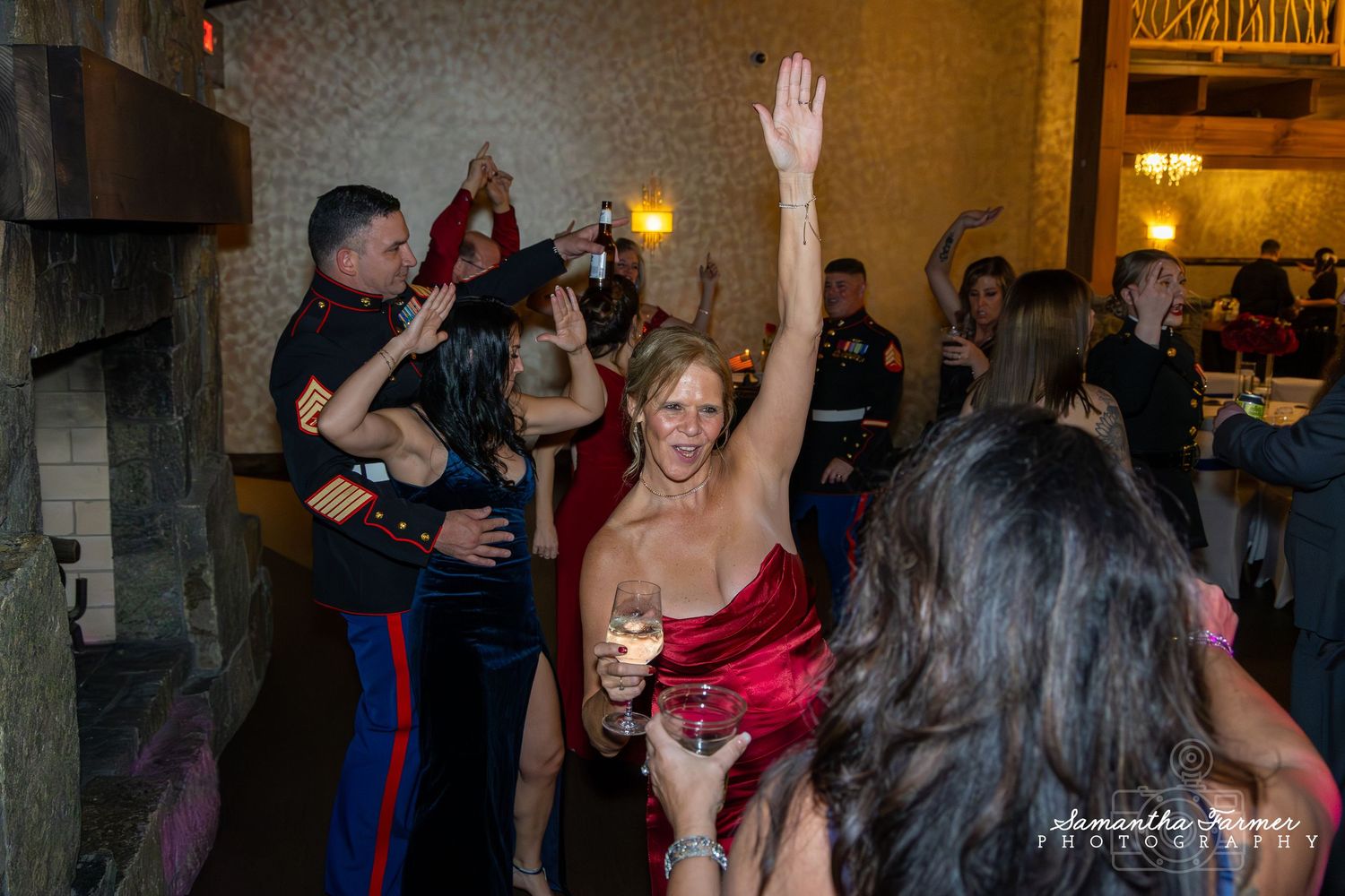 Party guests dancing and mingling at an evening celebration with warm lighting and brick wall backdrop.