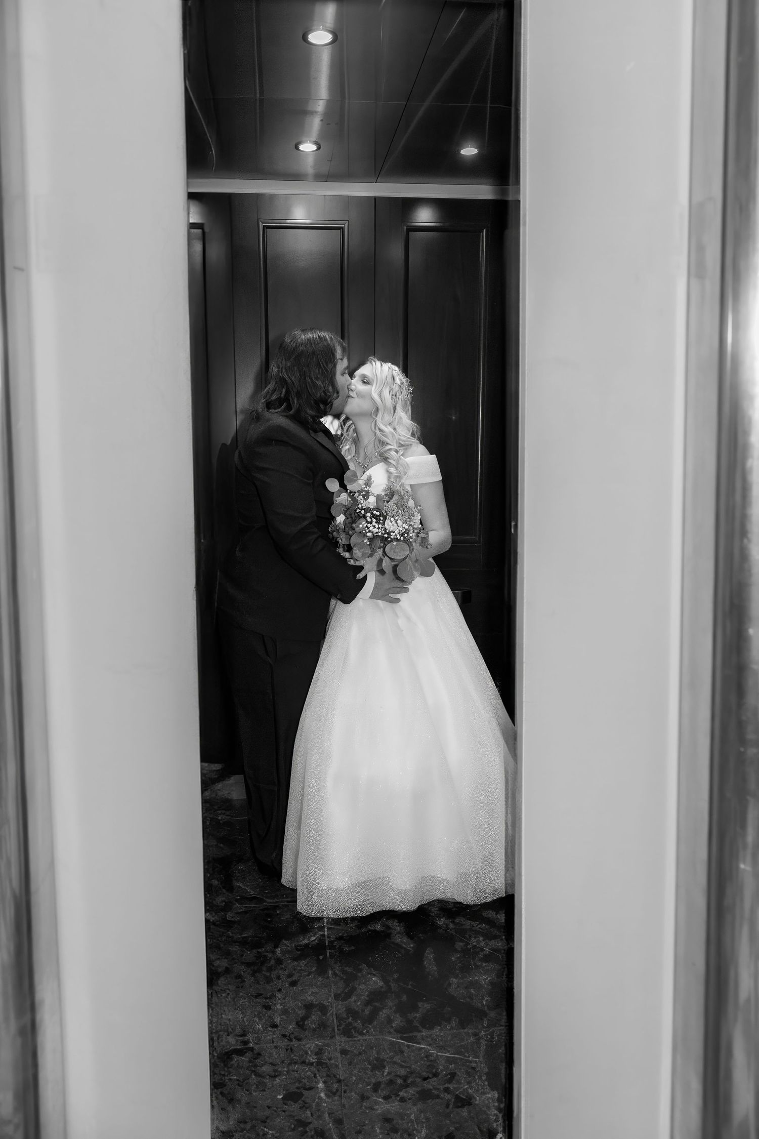 Elegant wedding couple silhouetted in hallway with dramatic lighting.