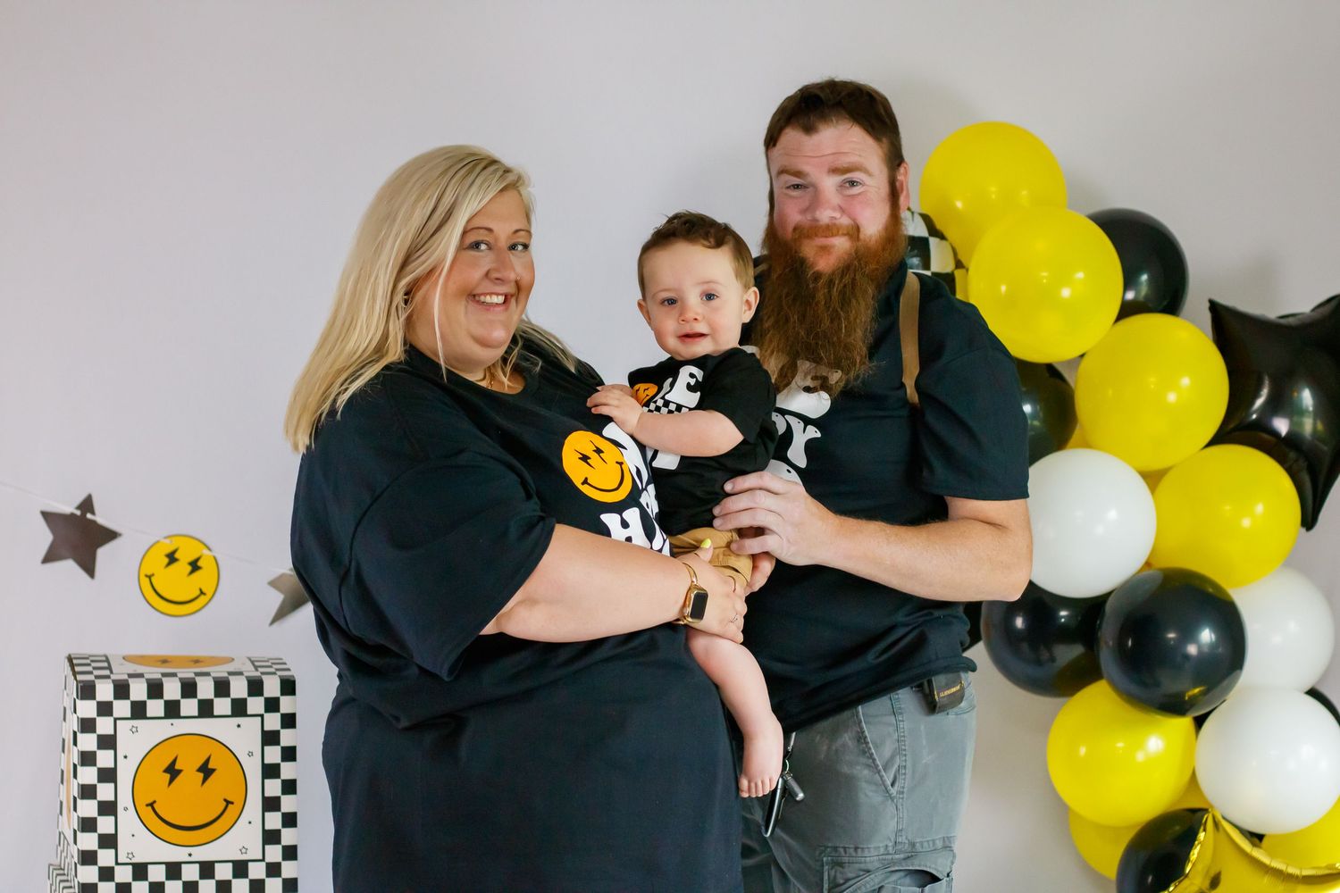 Family photo session with black and yellow balloon decorations in a studio setting.