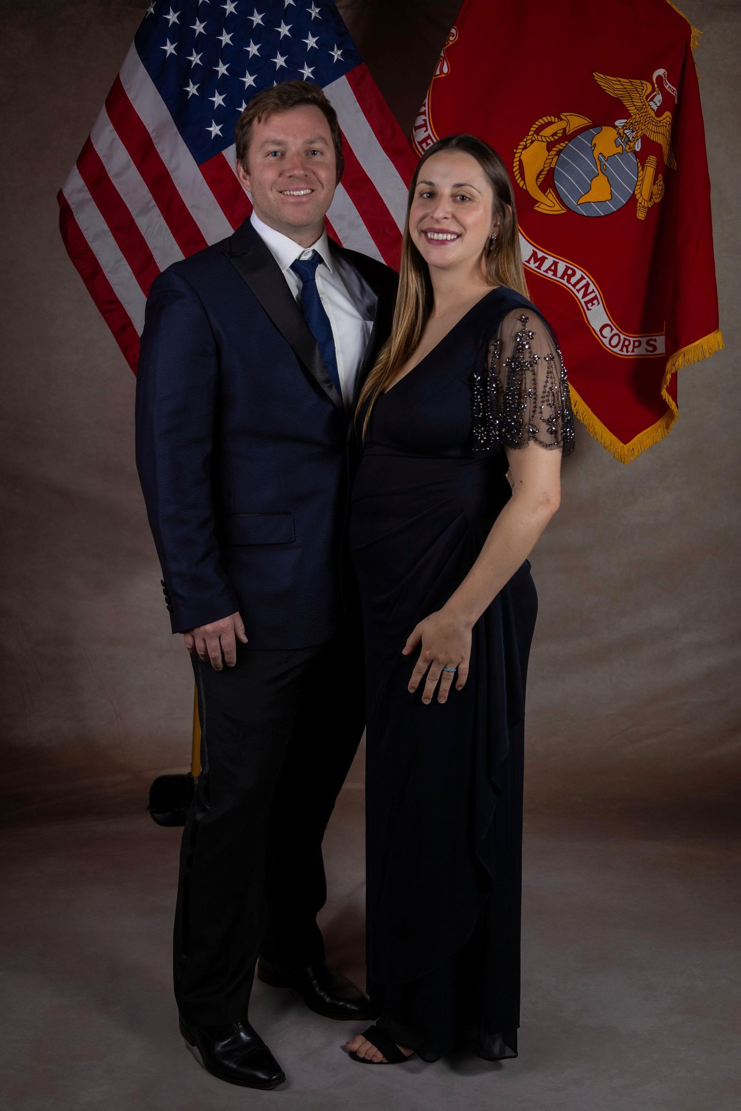 Formal portrait setup with American and Marine Corps flags against dark backdrop.