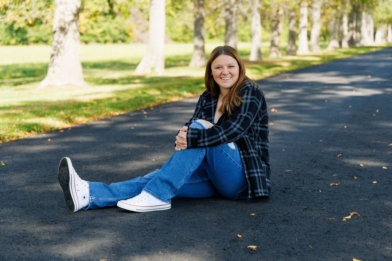 Casual outdoor portraits in plaid shirt and jeans on tree-lined path.