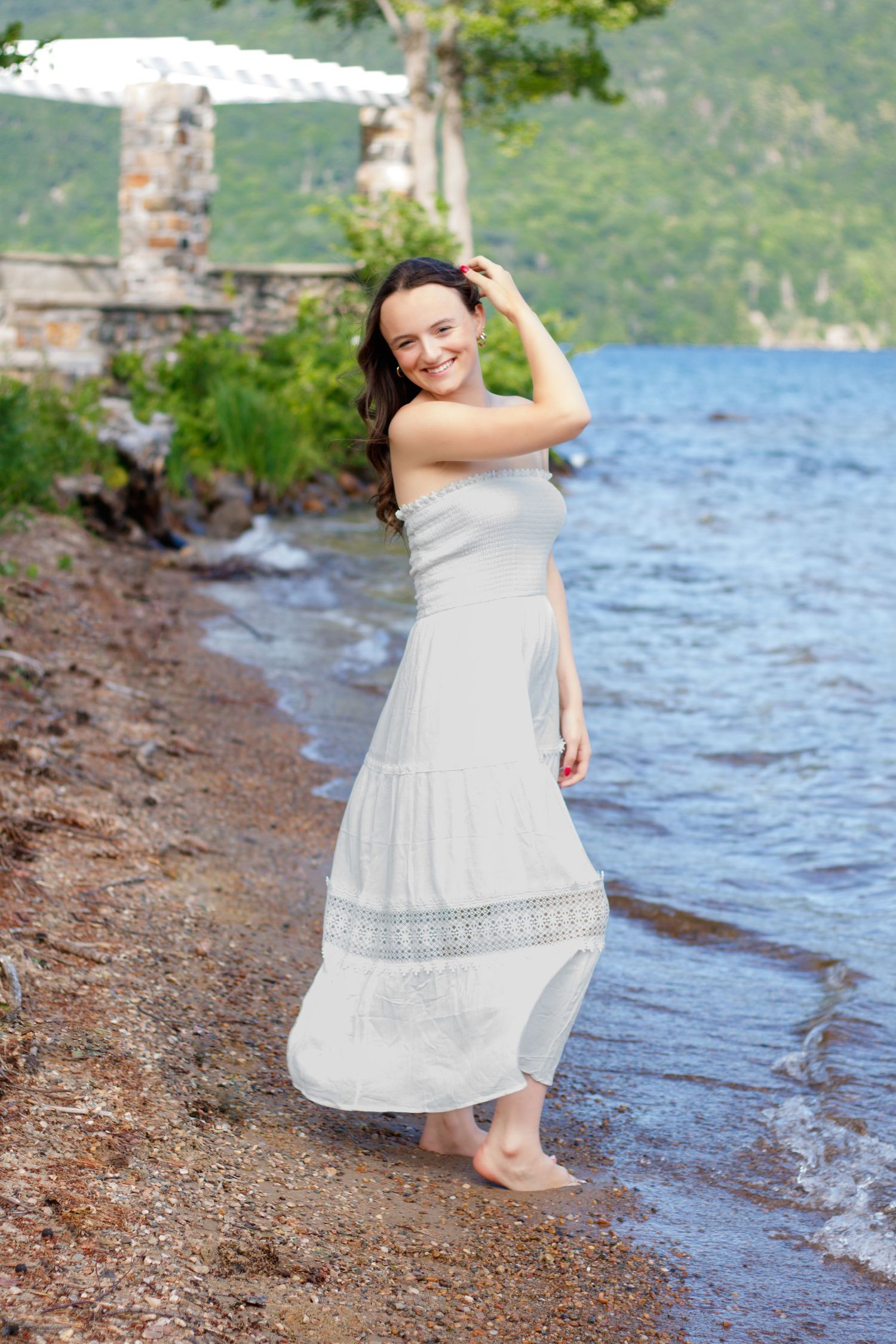 A white sundress worn by someone standing at the edge of a lake with mountains in the background.