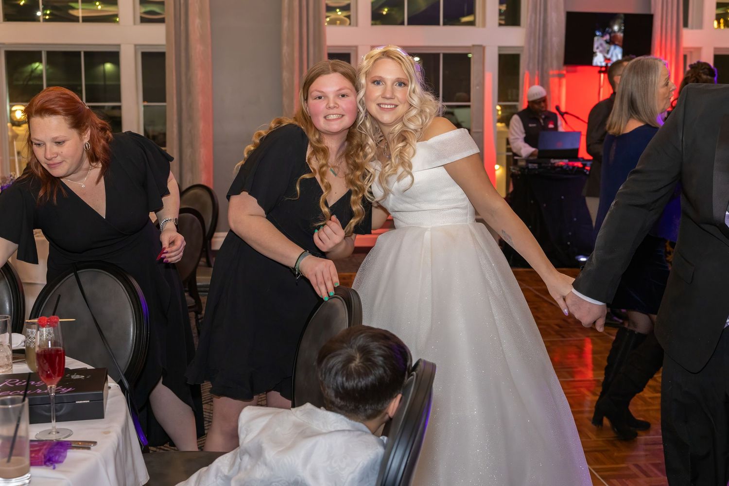 Wedding celebration in a grand ballroom with elegant decor and dancing guests.