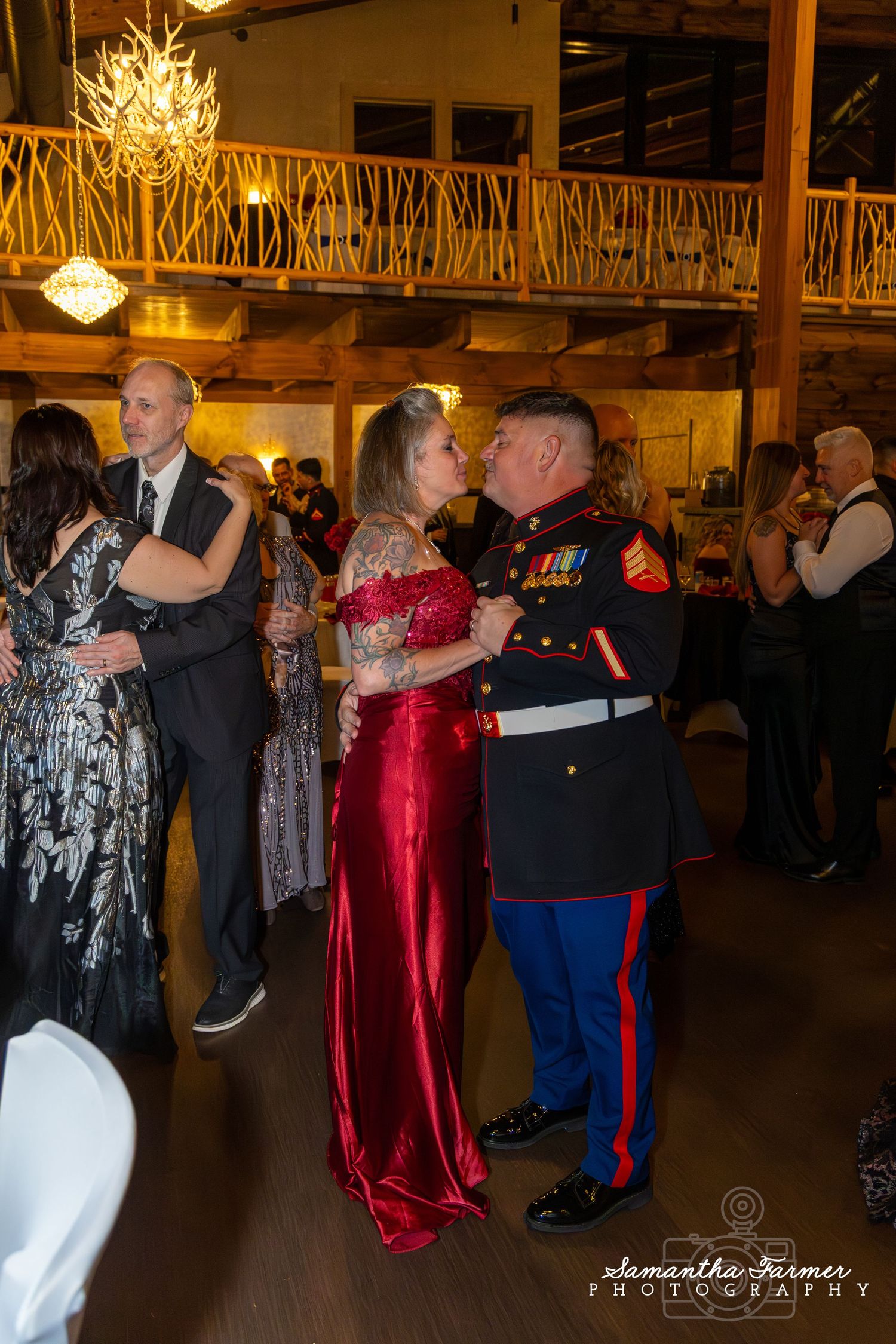 Formal ball with dancers in evening gowns and military uniforms under chandeliers.