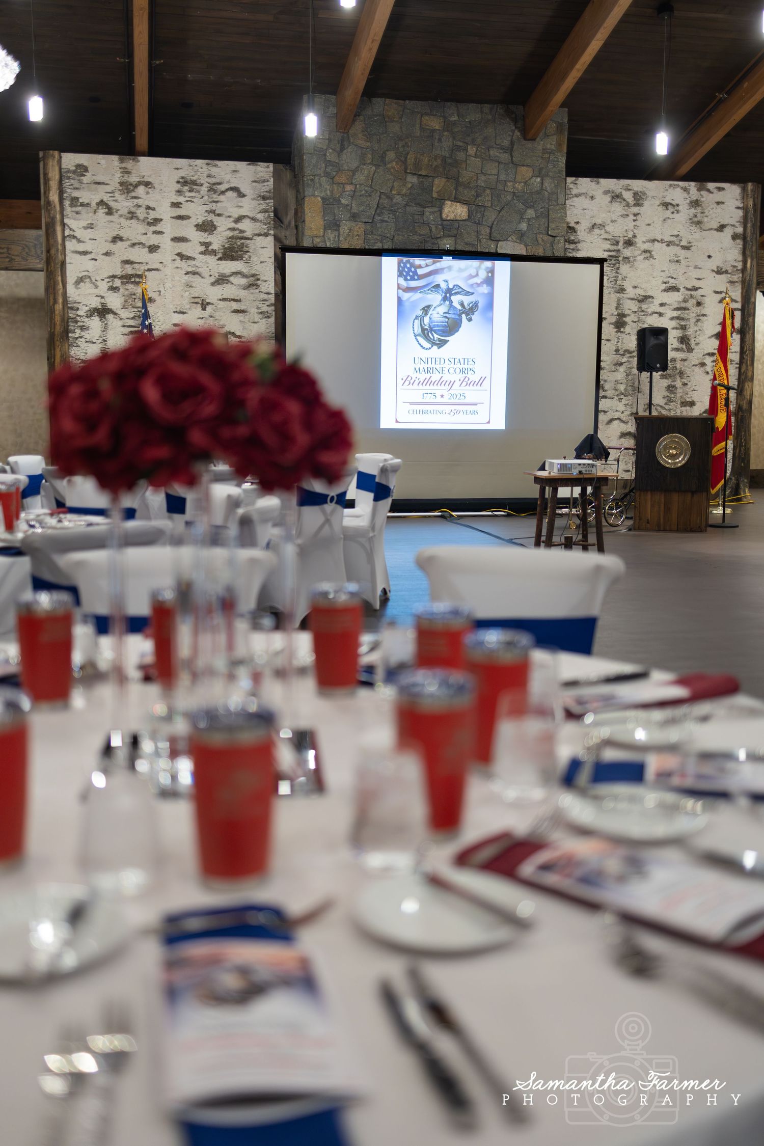 Banquet table settings with red and blue decor in rustic stone venue.