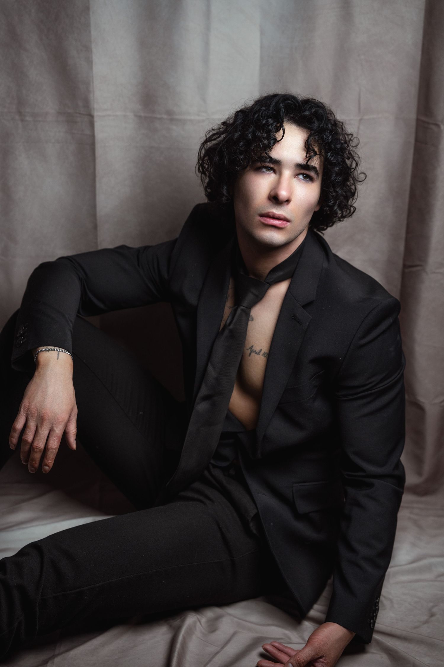 Artistic black and white fashion photo series showing model in dark blazer posing against neutral backdrop.