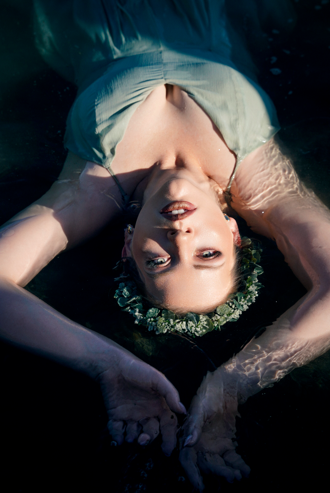 Ethereal underwater-style portrait with flowers and dreamy lighting effects.