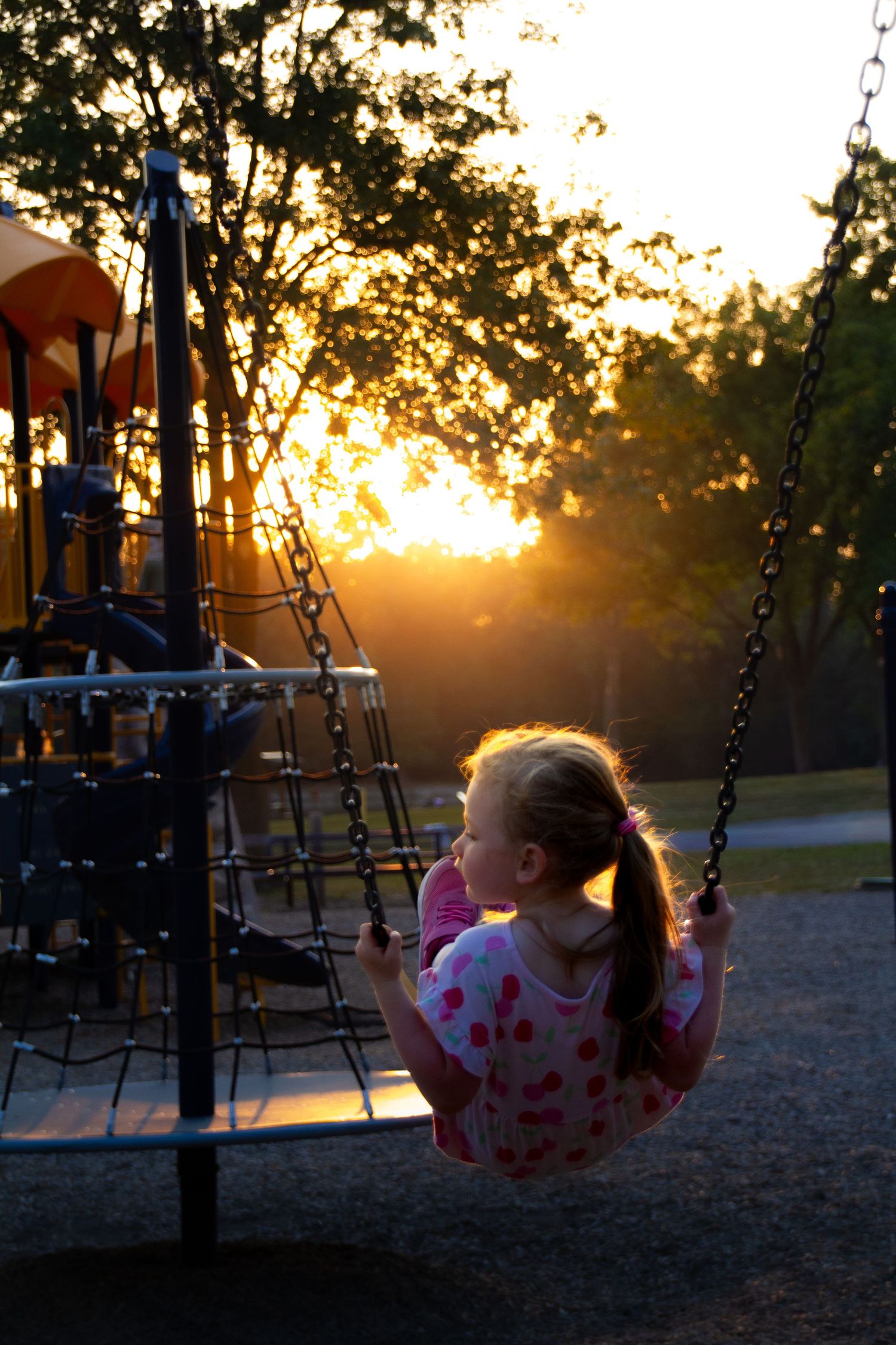Sunset photo of little girl on swing