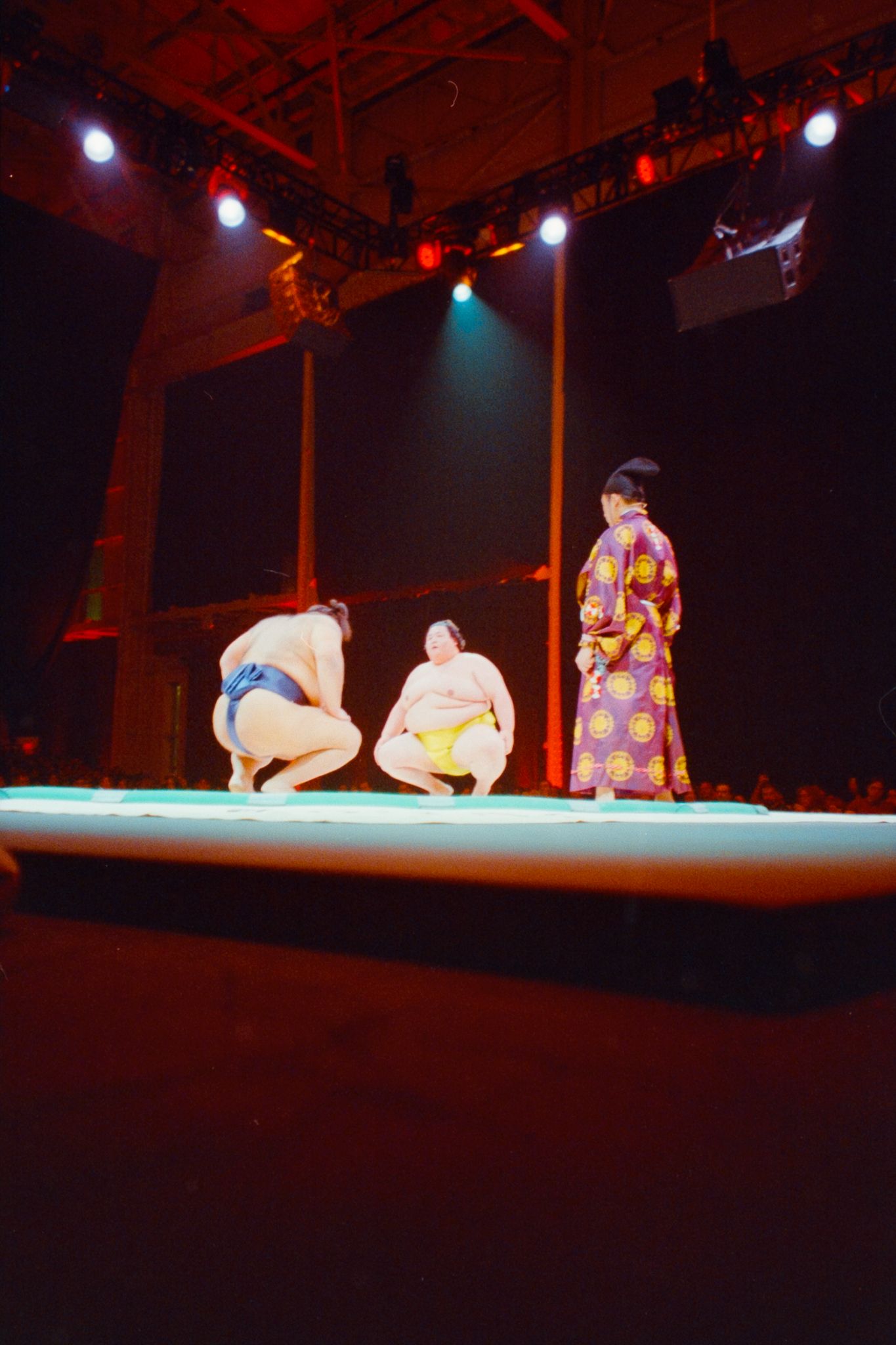 Stage performance with dramatic red lighting and multiple performers in traditional costumes.