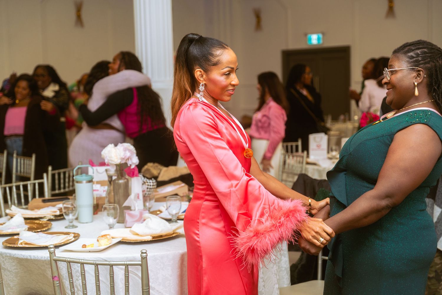 Event attendees interact at decorated white tables in a banquet hall setting.