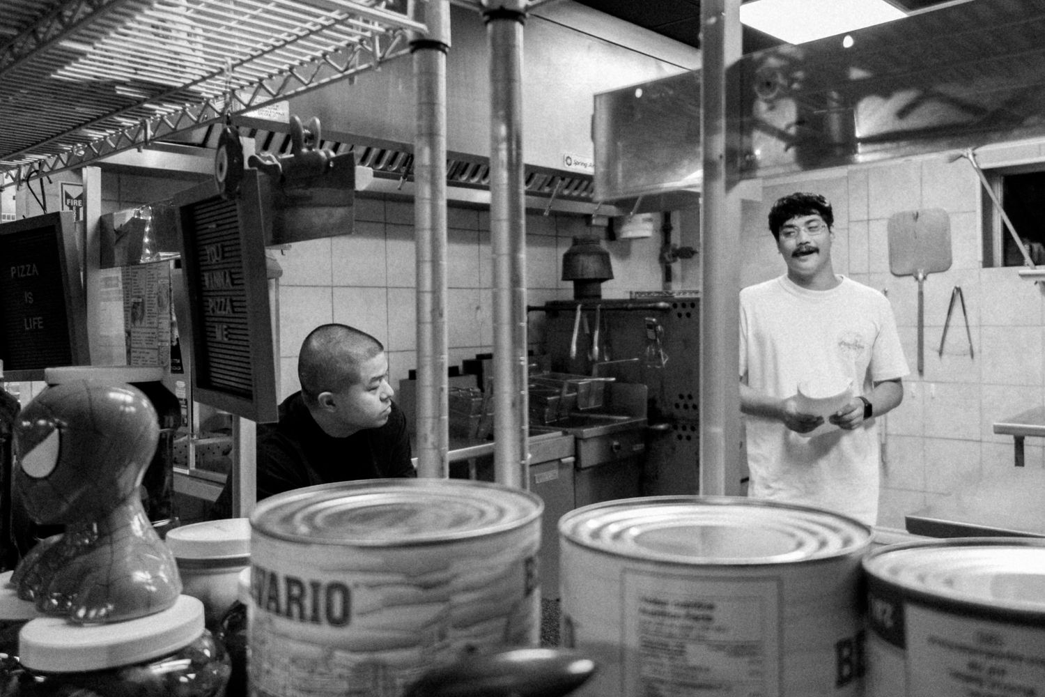 Industrial kitchen interior with stainless steel equipment and work surfaces.