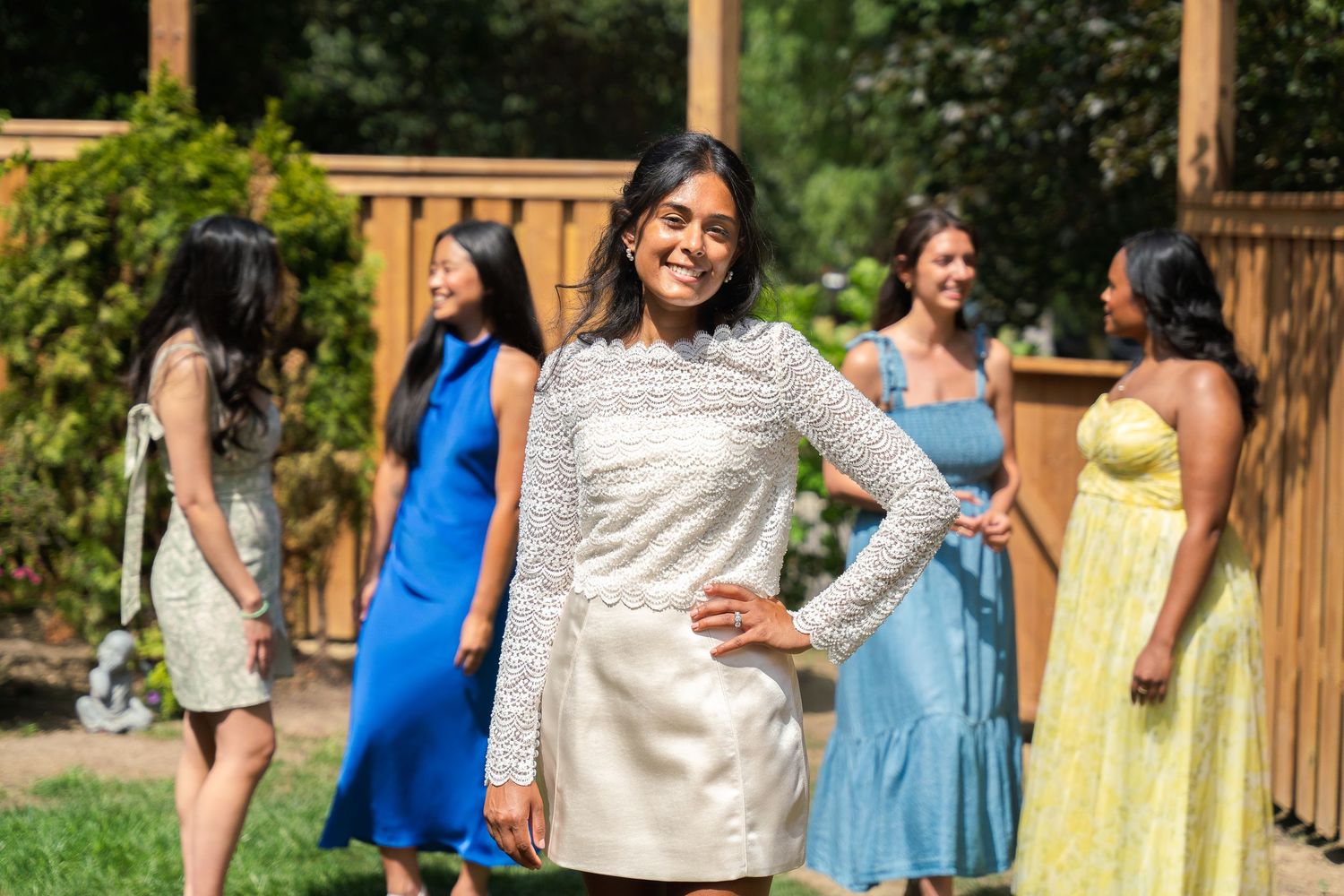 Guests mingling at a garden party with colorful summer dresses and outdoor decor.