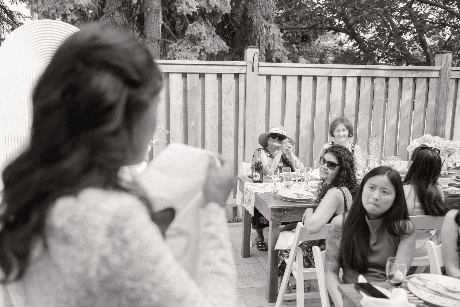 Black and white photo of guests enjoying conversation at an outdoor celebration.