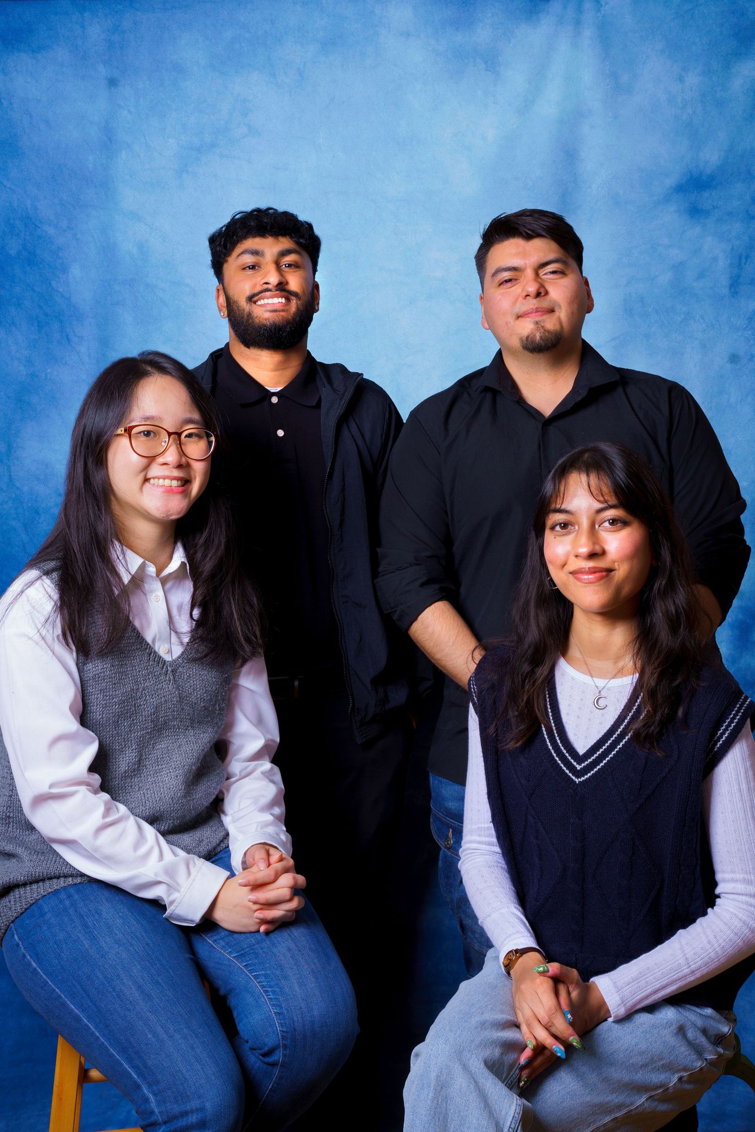 Family group poses together in casual attire against blue studio background.