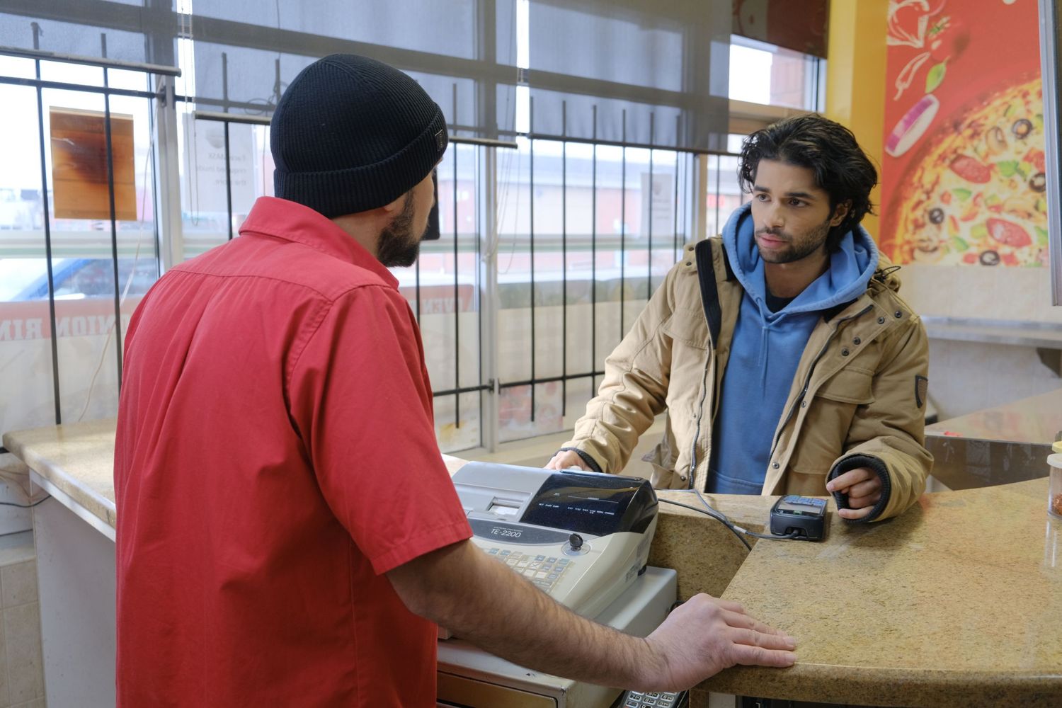 Customer and employee having a conversation at a service counter with gestures and body language.