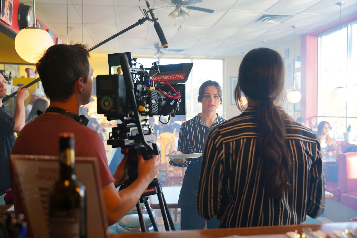 Behind the scenes view of camera operators filming in a restaurant setting.