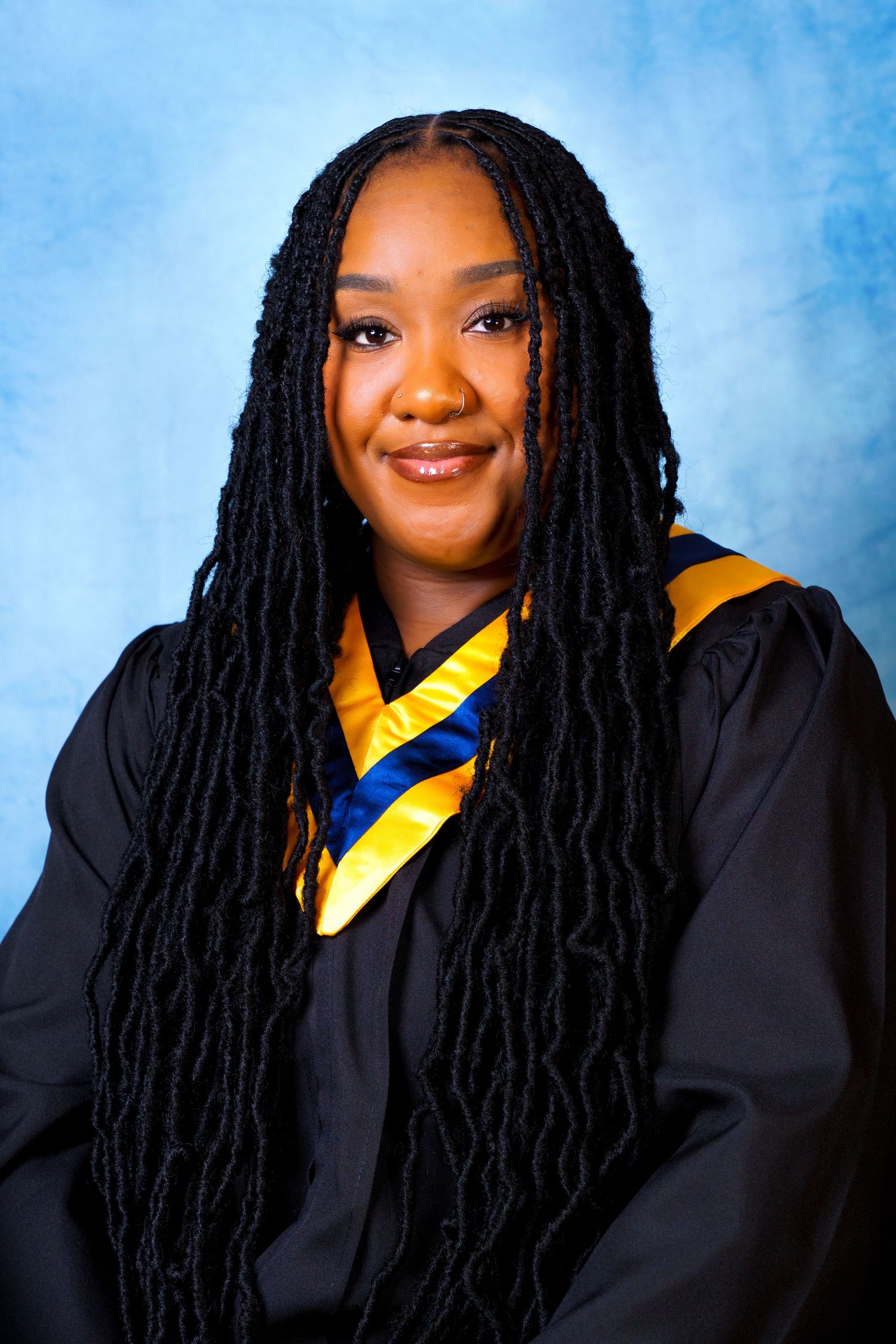 Graduate in academic regalia with yellow stole against blue background.