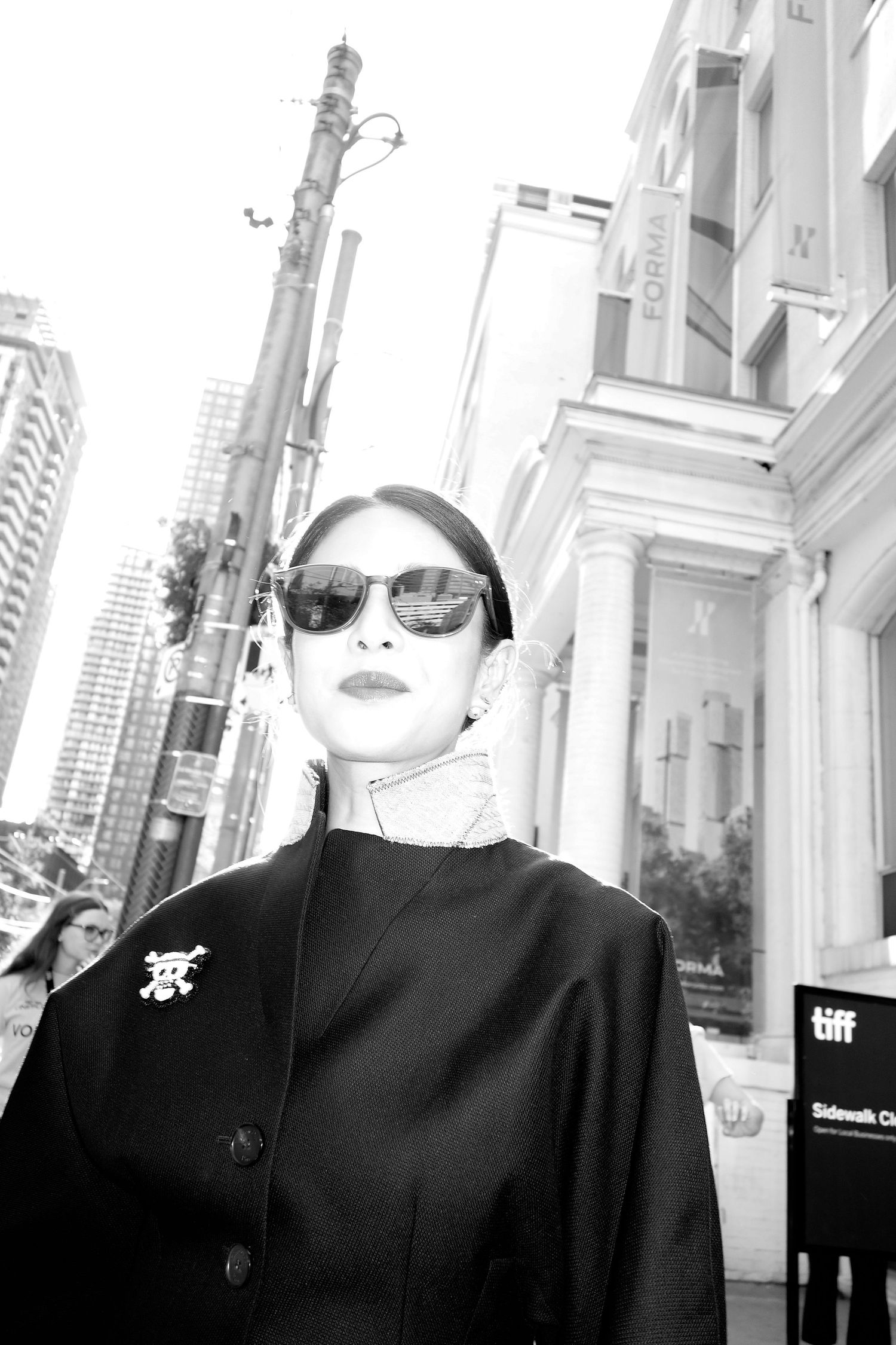 Artistic black and white portrait of person wearing sunglasses in urban setting.