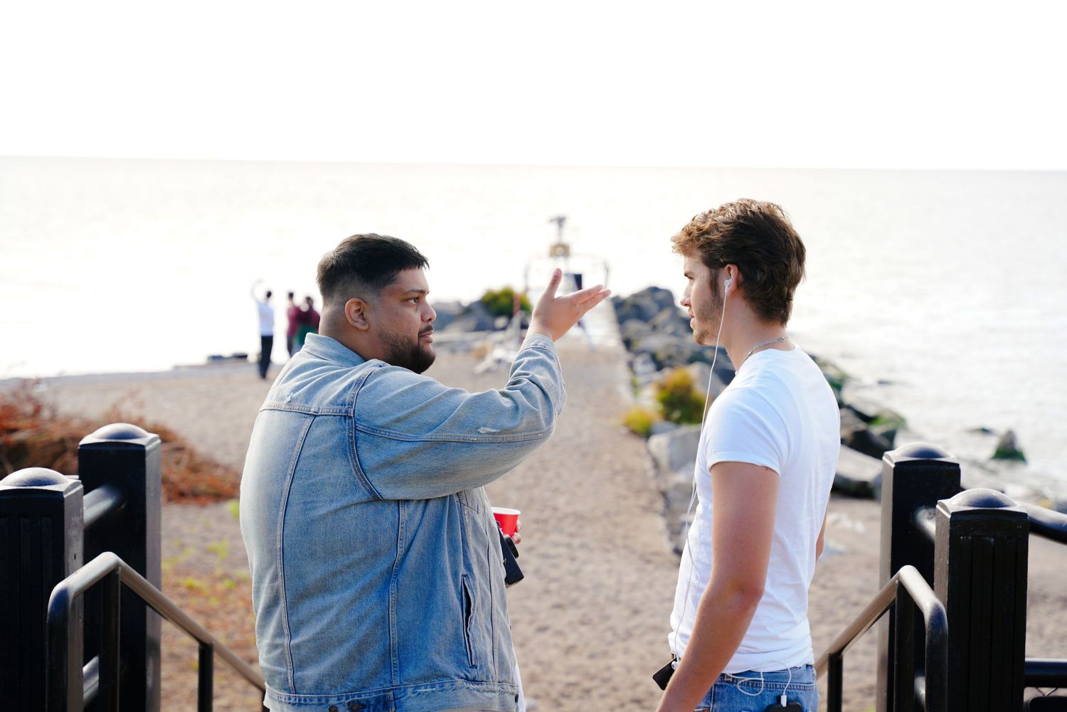 Film crew members work together on a beach during a sunny day shoot.