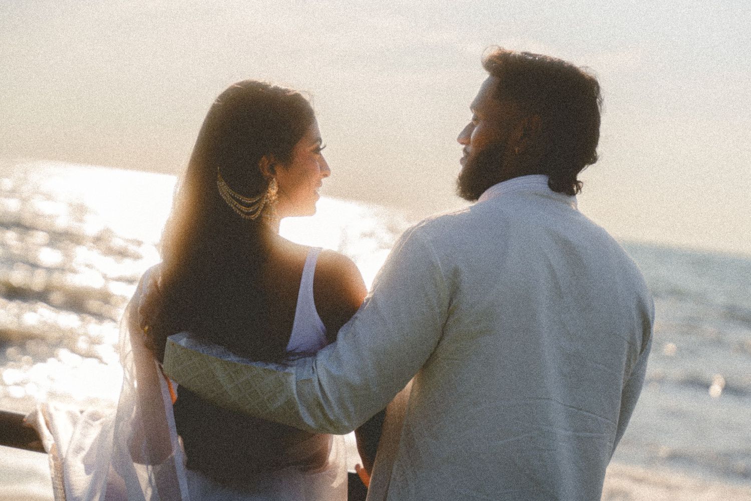 Romantic couple silhouettes walking along the beach at sunset.