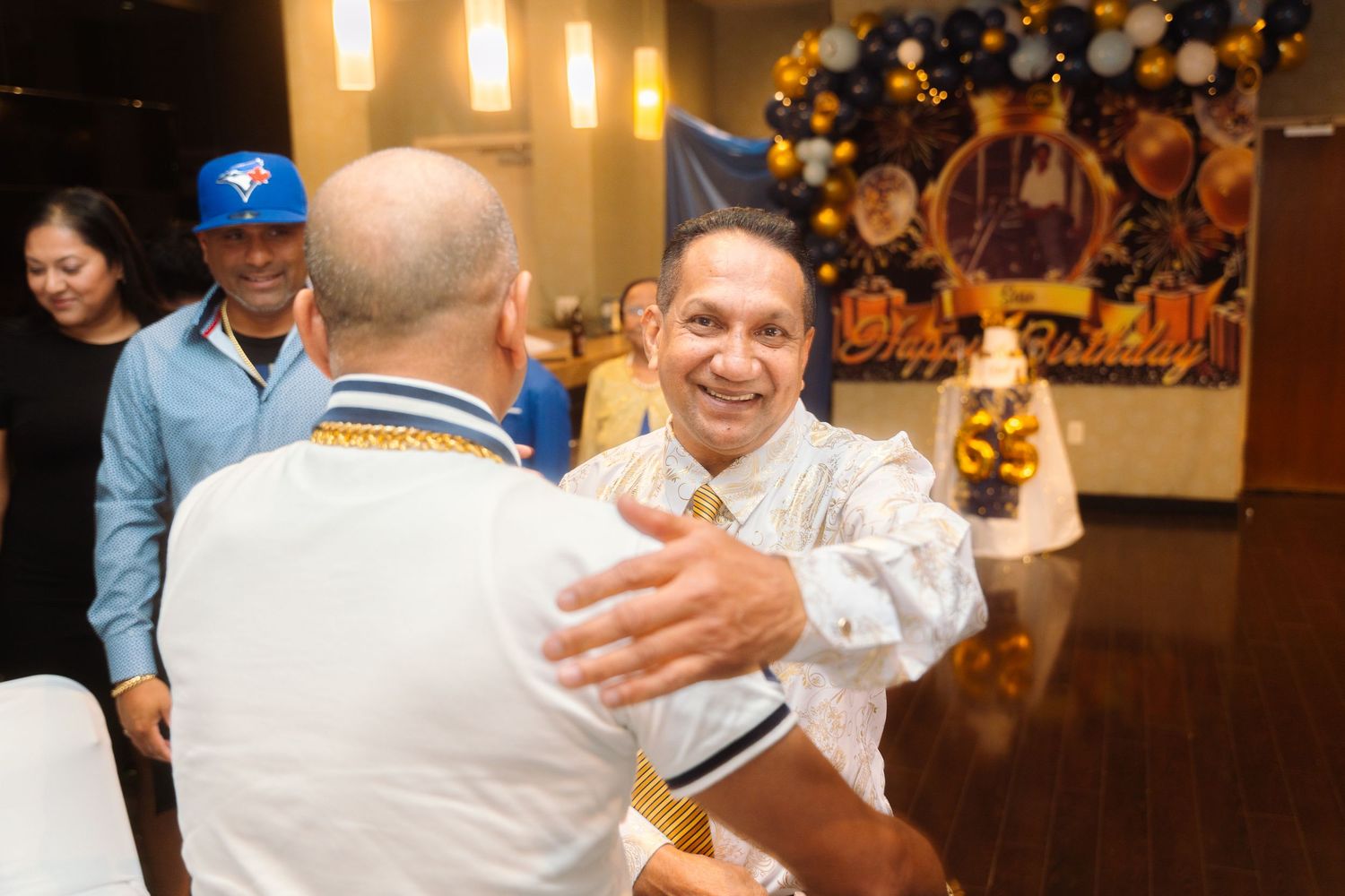 People celebrating at an indoor event with Halloween decorations visible in the background.