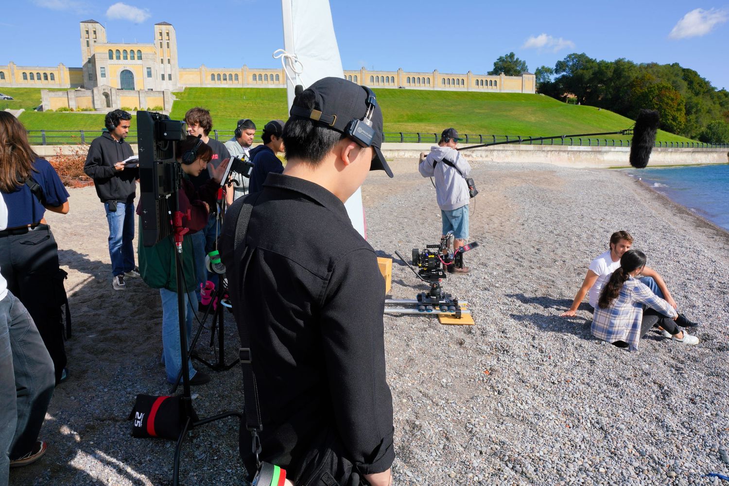 Production team filming on location near a historic building with camera equipment.