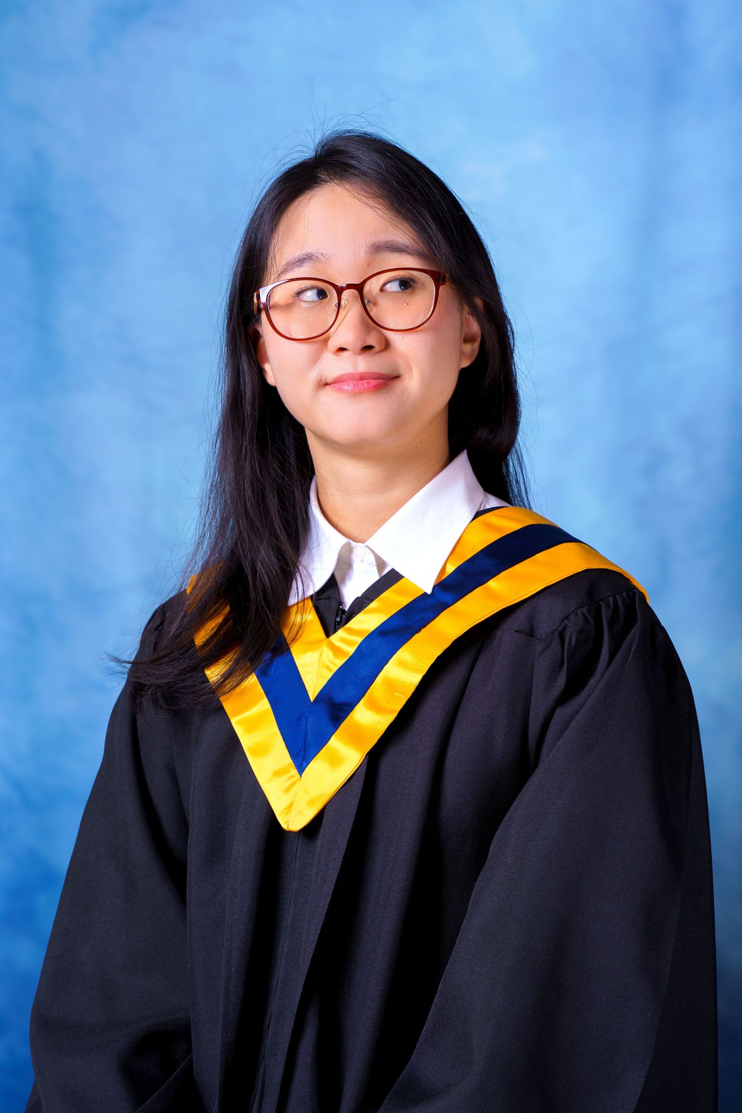 Graduate wearing glasses and academic regalia poses for graduation photos.