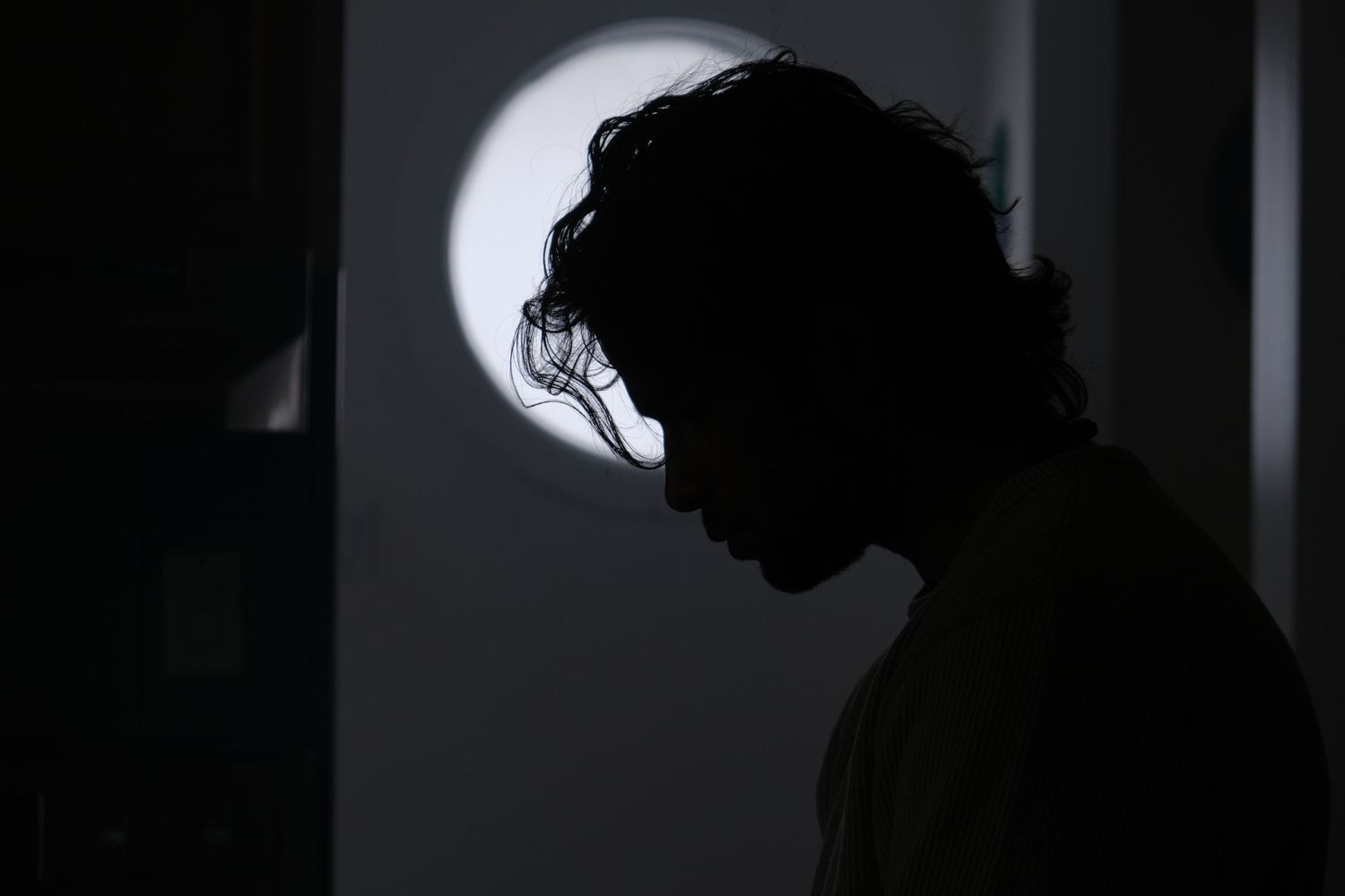 Silhouettes of figures against a bright window background.