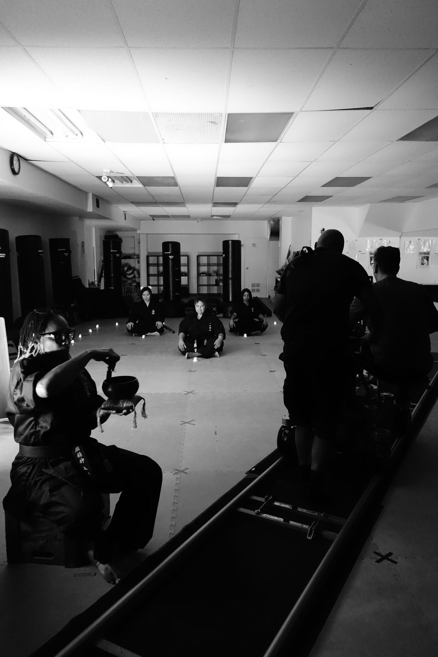 Dark silhouettes of people filming in an empty martial arts training facility.