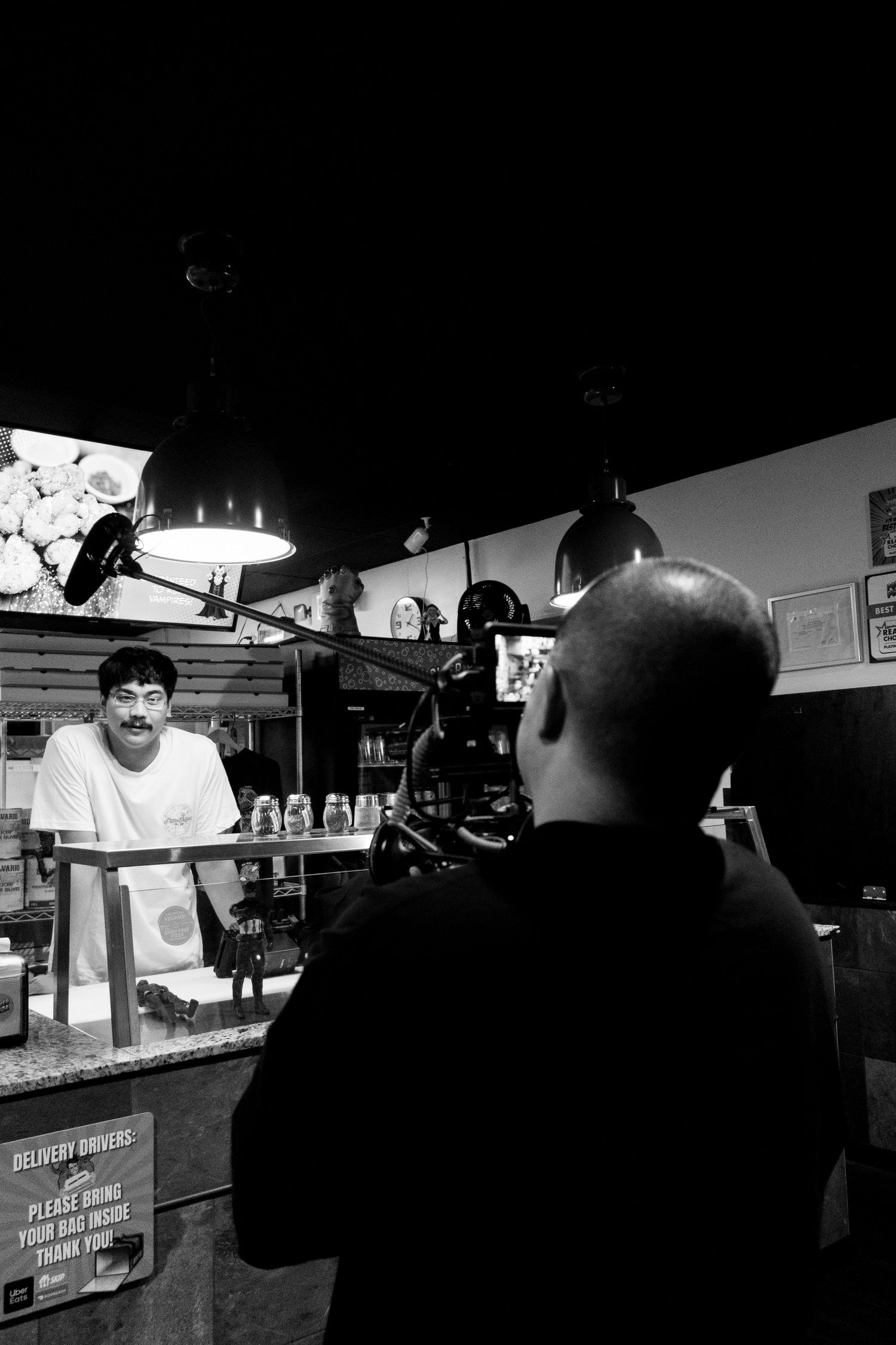Dark interior of a counter service area with silhouettes and overhead lighting.